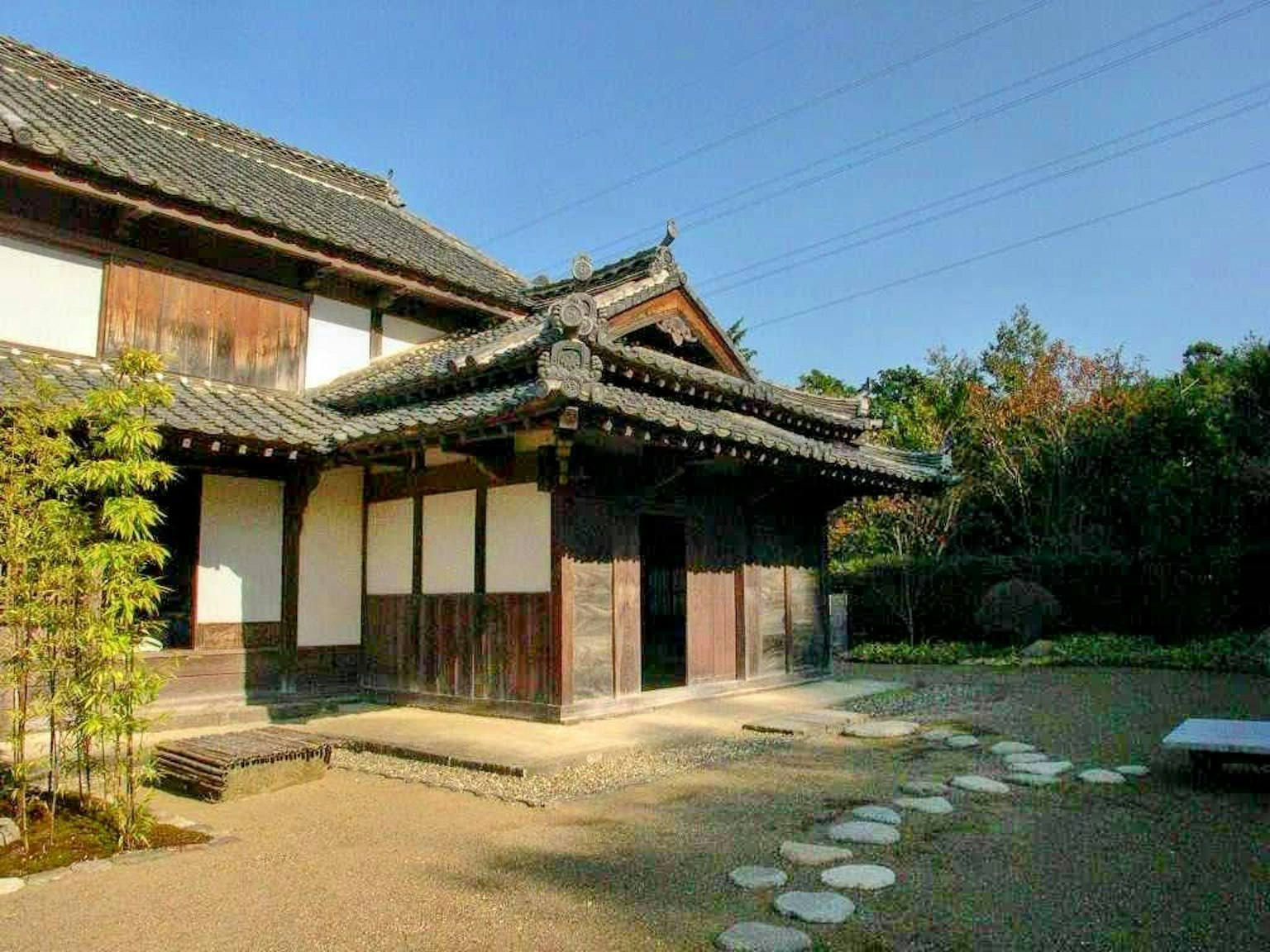 传统日本房屋外观，配有郁郁葱葱的花园和石头小径