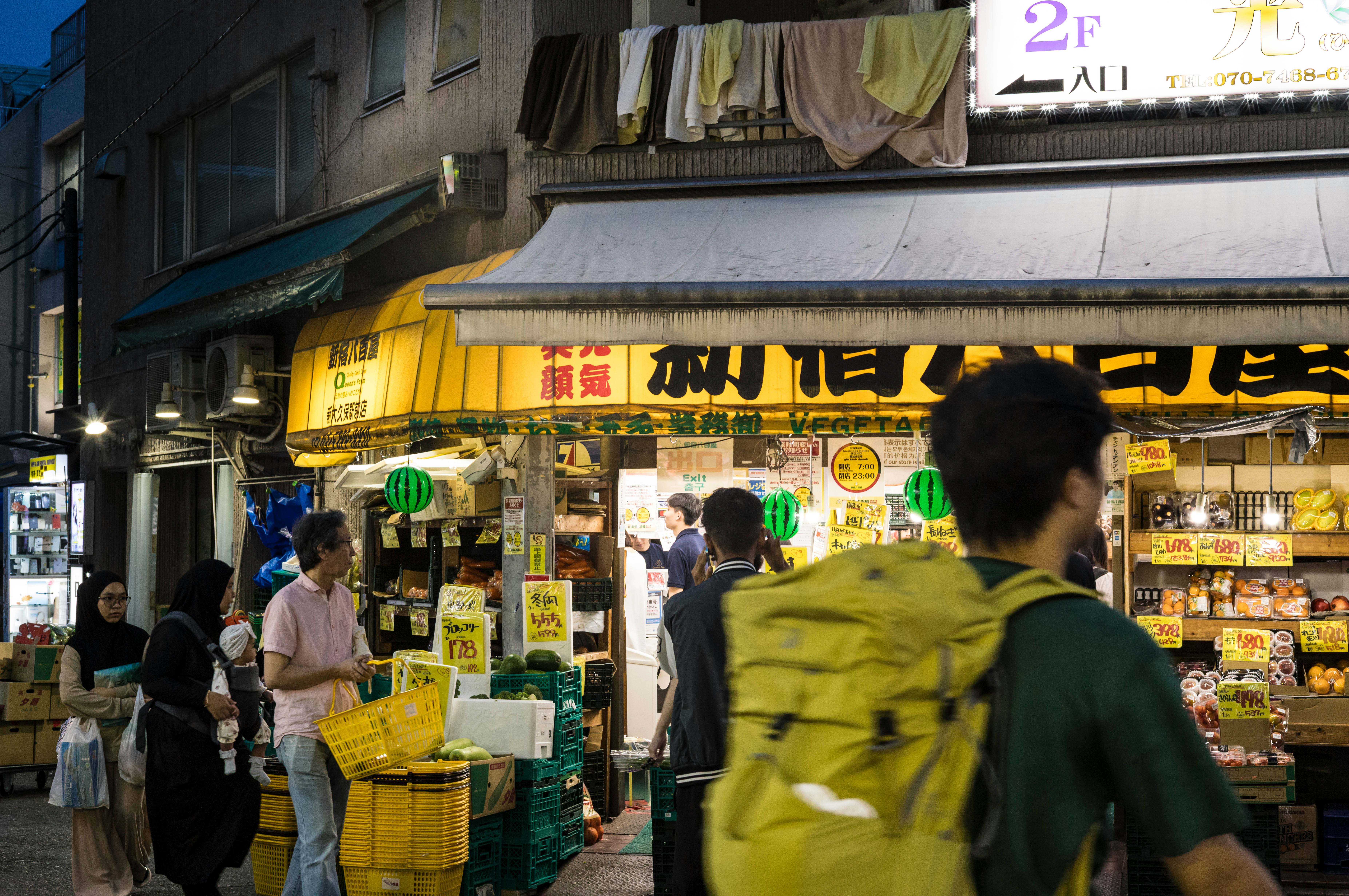 商店街の軒先に並ぶ看板と買い物客の行き交い