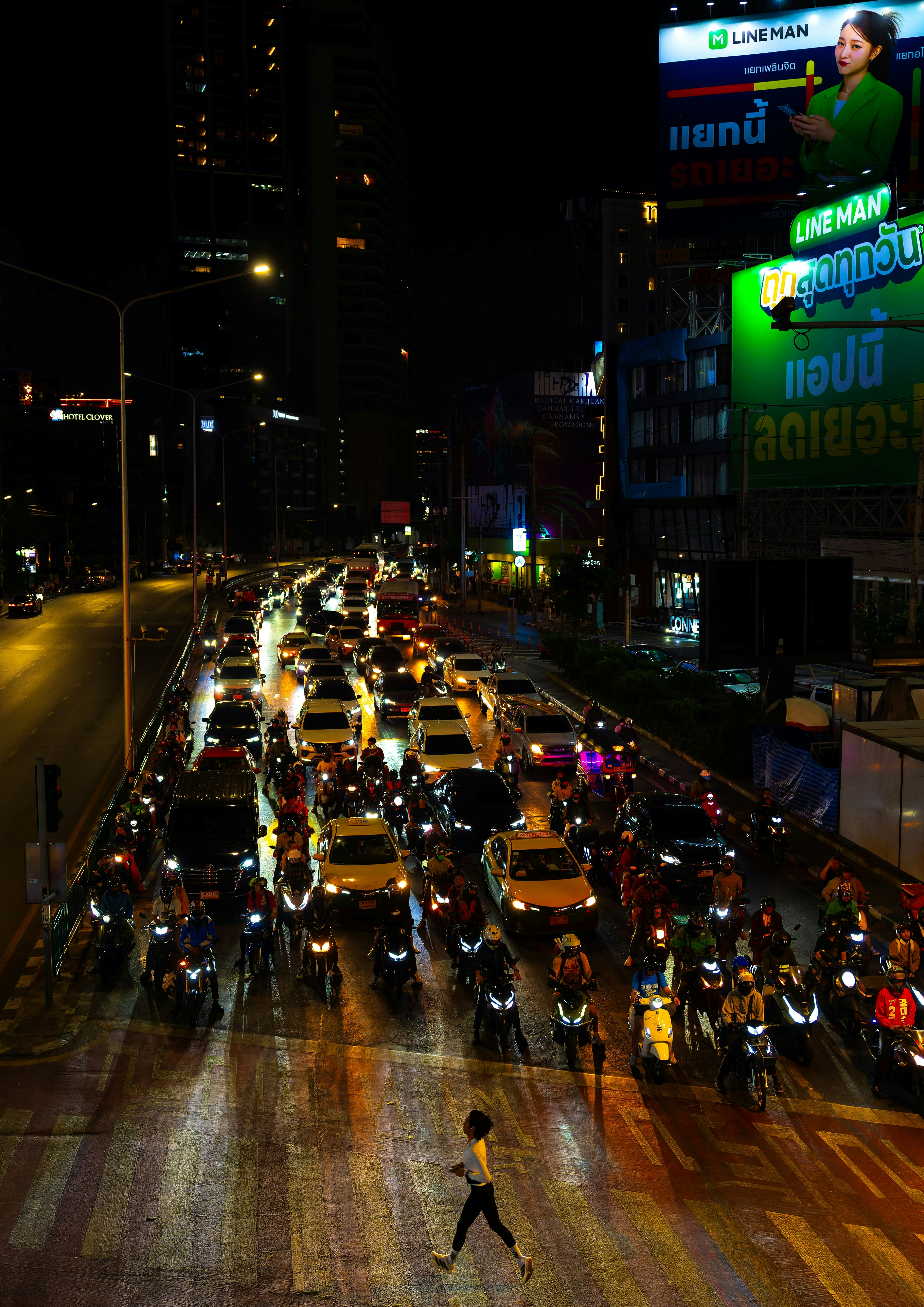 夜の大通りを走る車とバイクの渋滞、ネオン看板のあるバンコクの街並み