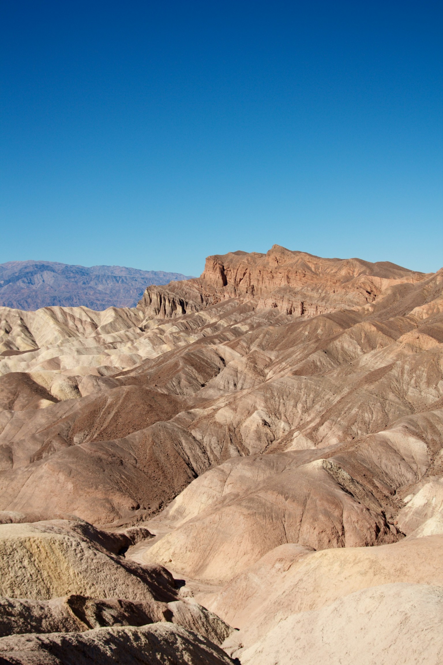 Eine unebene Landschaft mit geschichteten braunen Hügeln unter einem klaren blauen Himmel