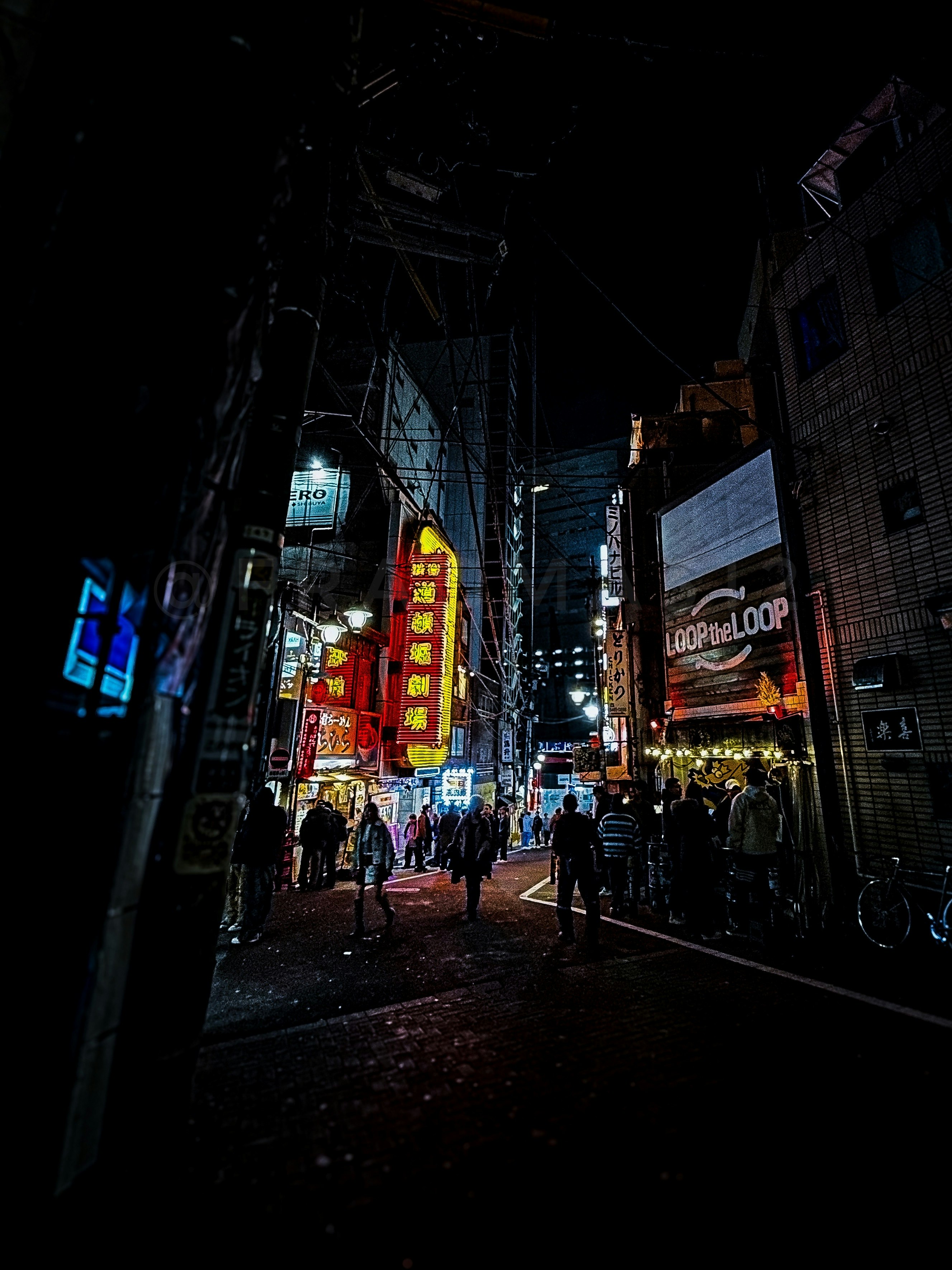 夜の繁華街でネオン看板が並ぶ路地