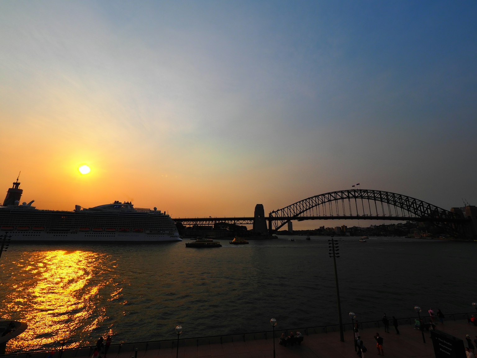 Jembatan Pelabuhan Sydney dan matahari terbenam yang terpantul di air