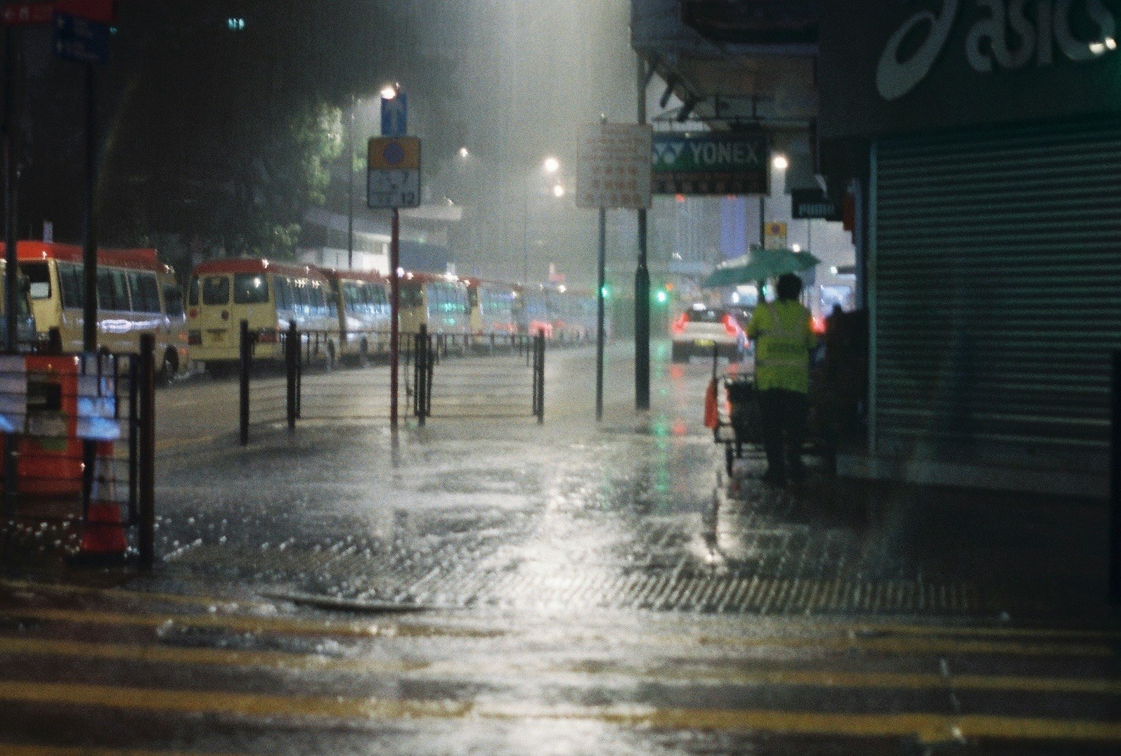 雨の夜の街角で濡れた歩道と車のライトがにじむ