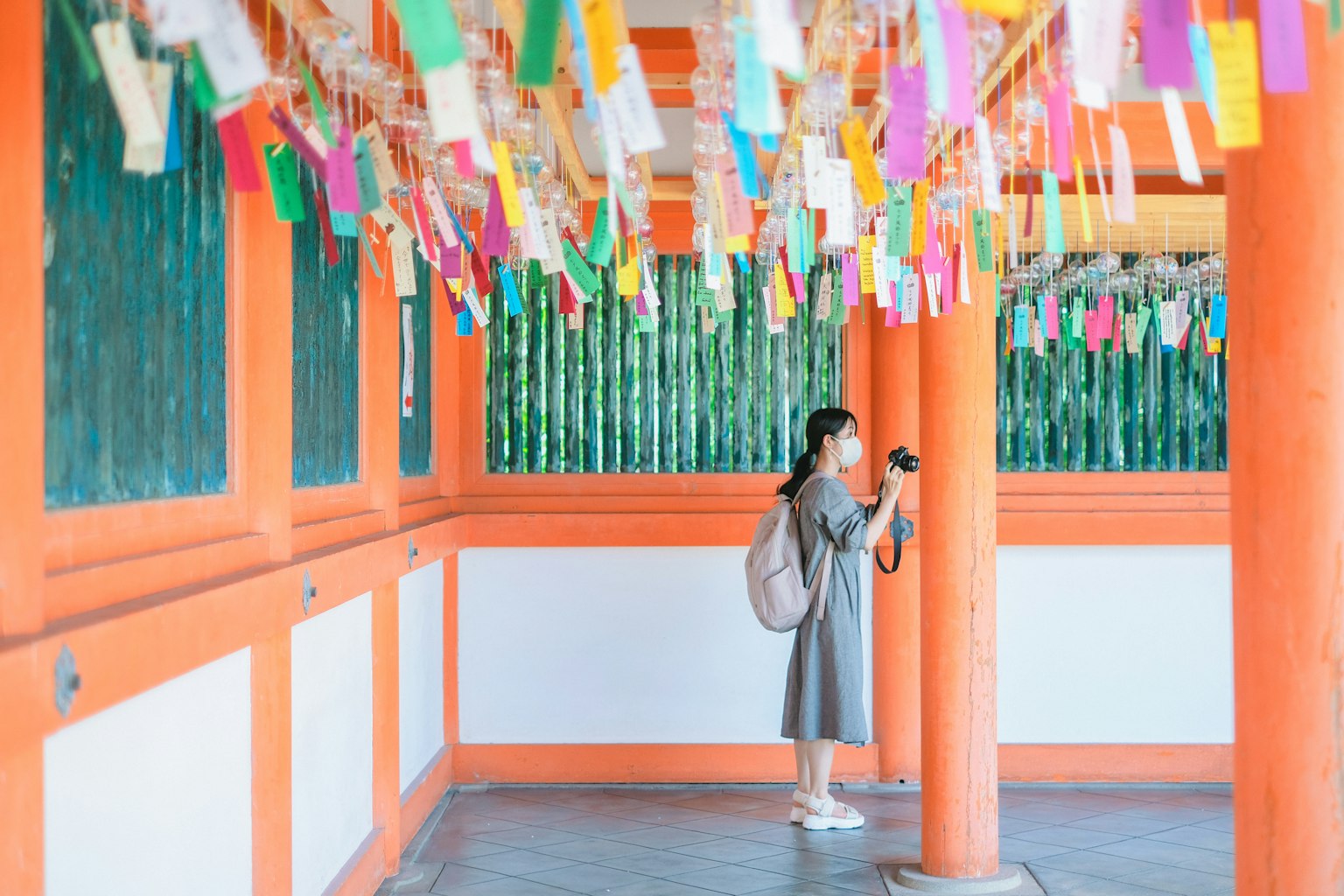 Una mujer de pie en un espacio con columnas naranjas y tiras coloridas colgando arriba