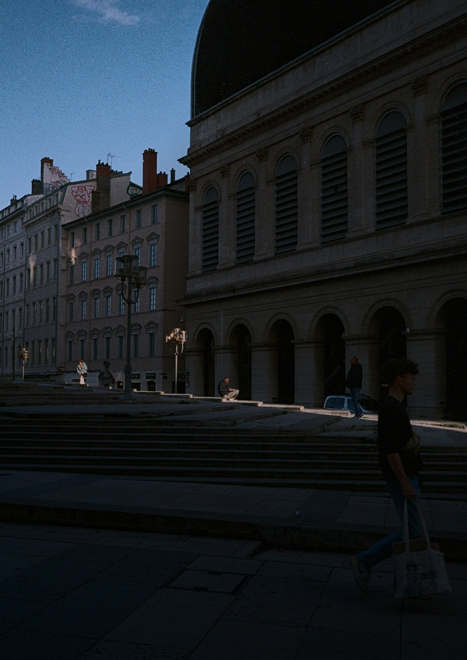 暗い通りに立つ人影と建物の影が交差する風景