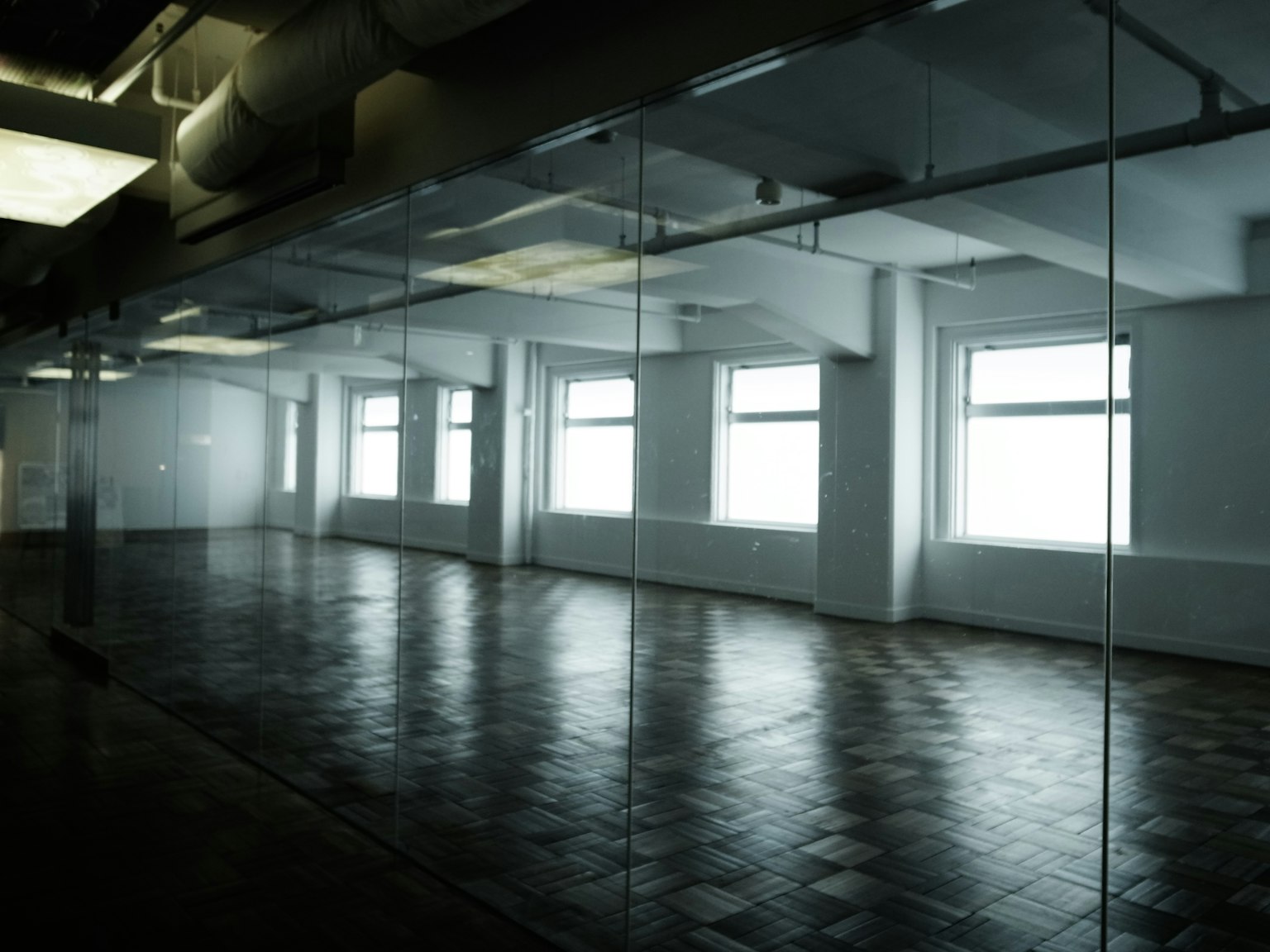Espacio de oficina vacío con una pared espejo que refleja ventanas