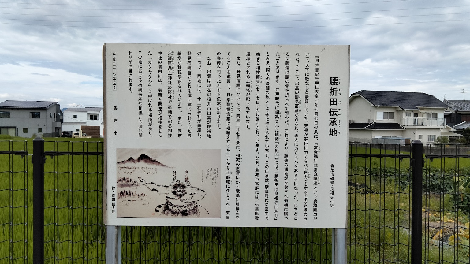一块有日文文本和历史照片的标志在草地上