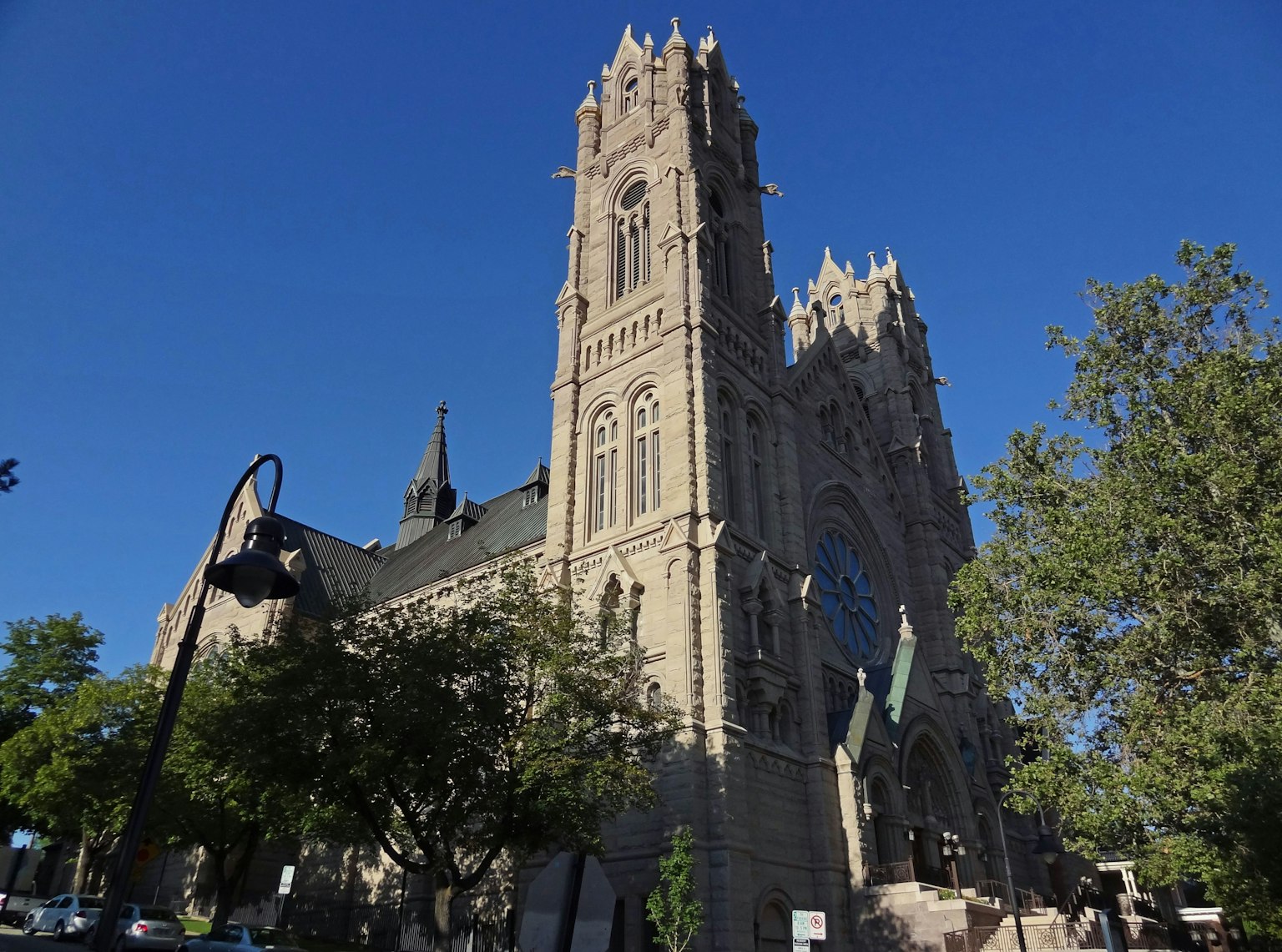 Belle façade d'église de style gothique avec de grands tours et de la verdure sous un ciel bleu