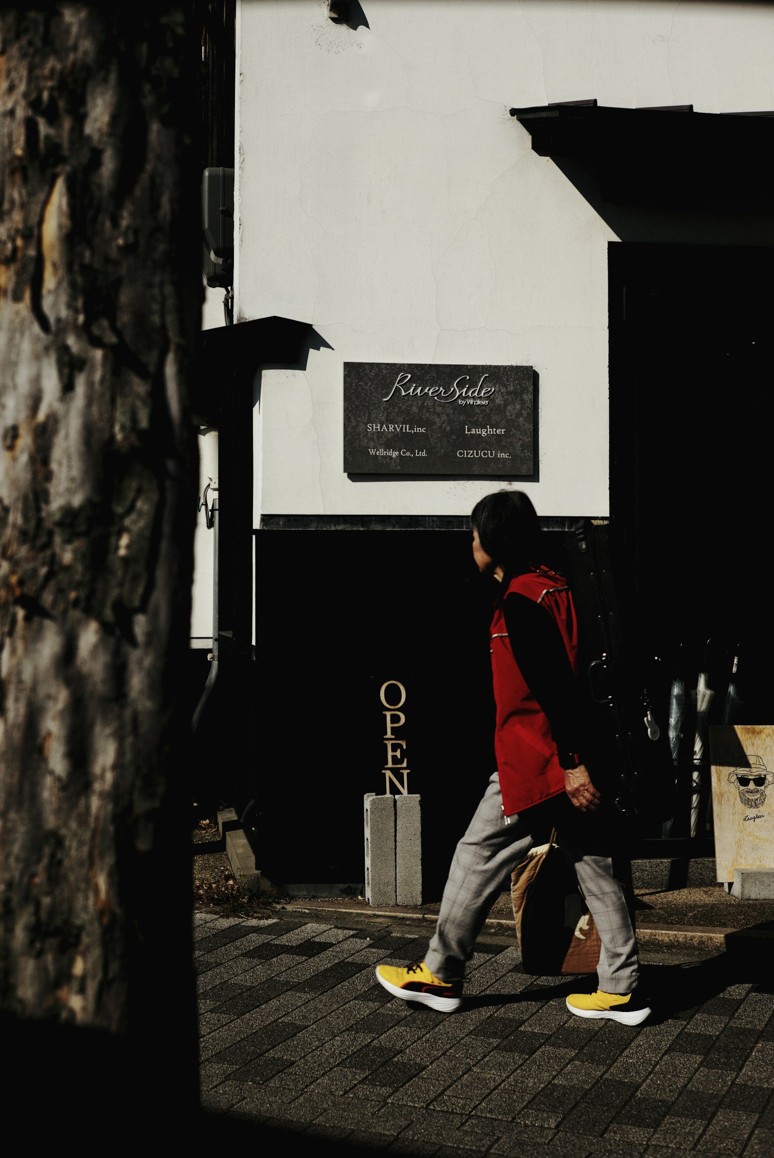 Một người đàn ông mặc áo đỏ đi bộ trước một cửa hàng có biển mở