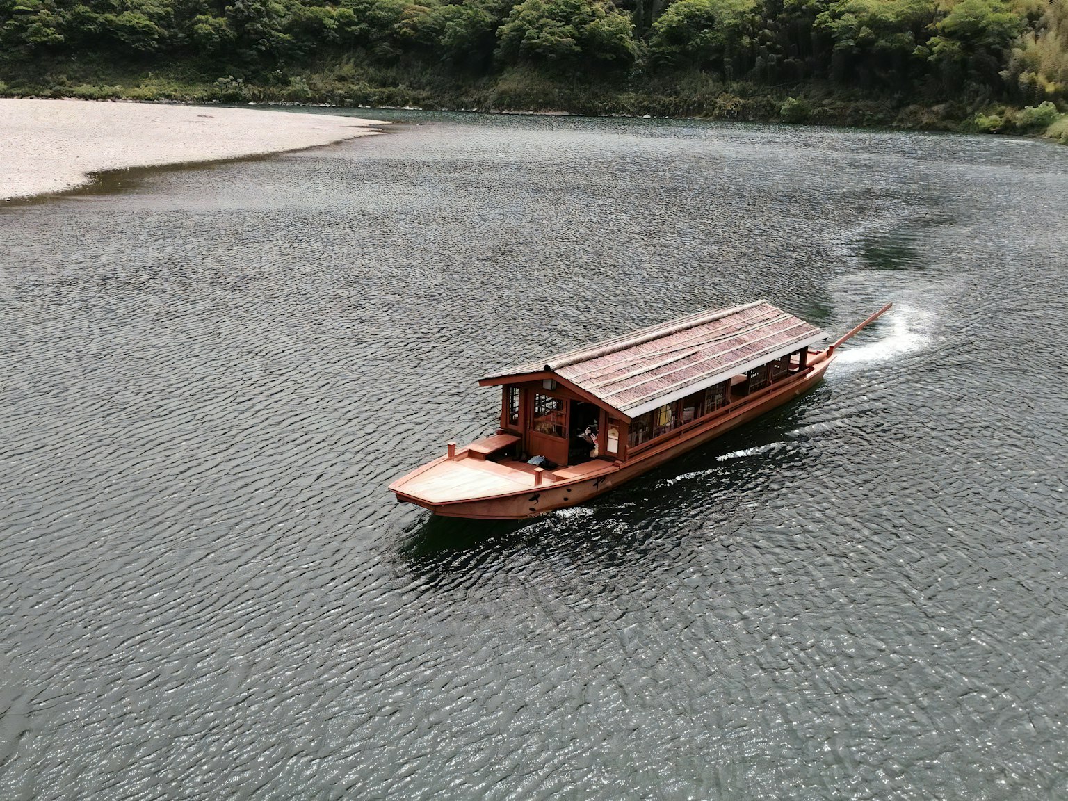 Thuyền gỗ di chuyển trên sông với bờ xanh