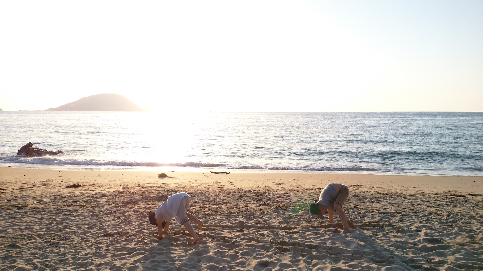 เด็กๆ เล่นที่ชายหาดพร้อมกับพระอาทิตย์ตกเหนือมหาสมุทร