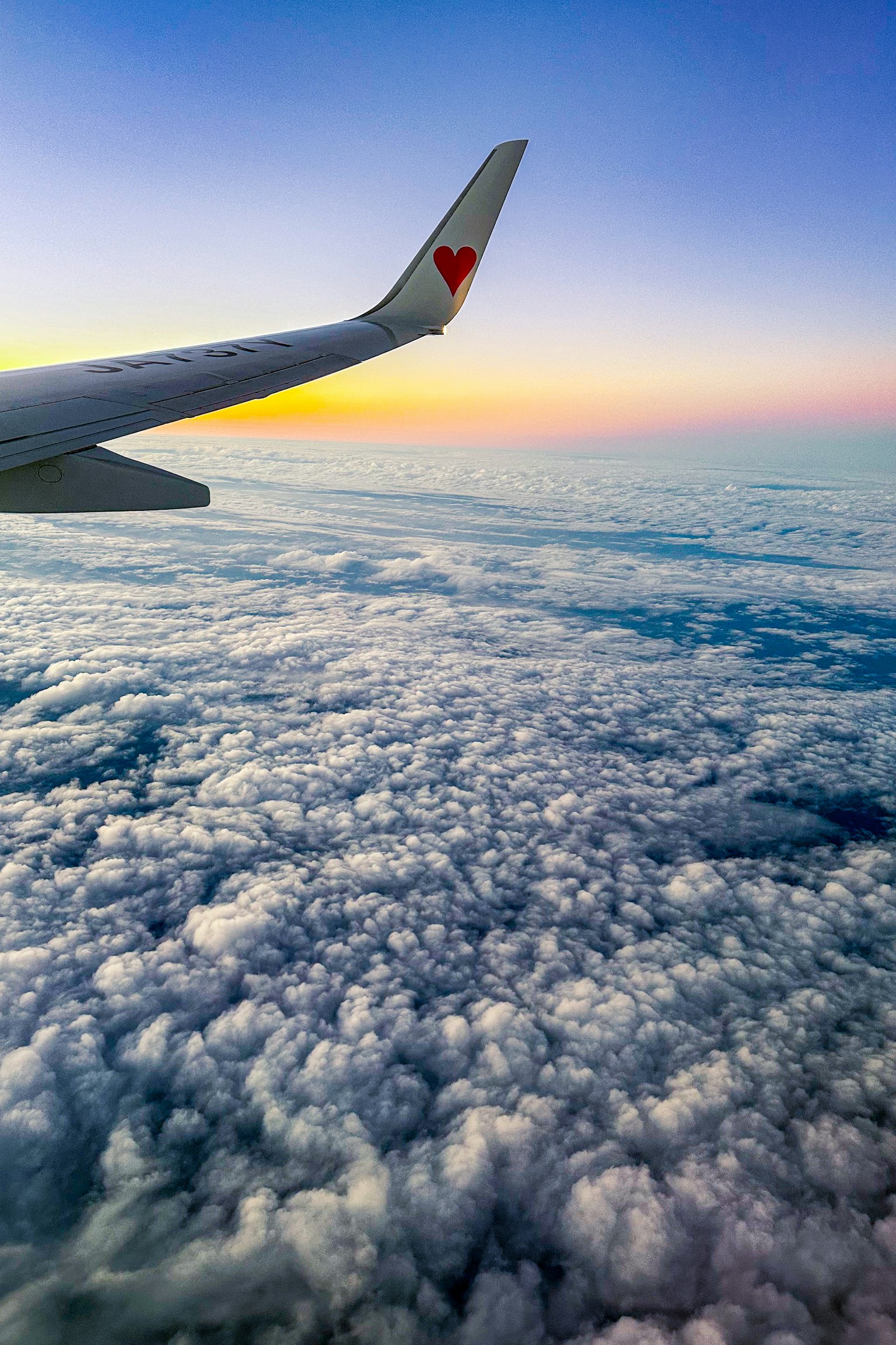 Flugzeugflügel über einem Wolkenmeer bei Sonnenuntergang