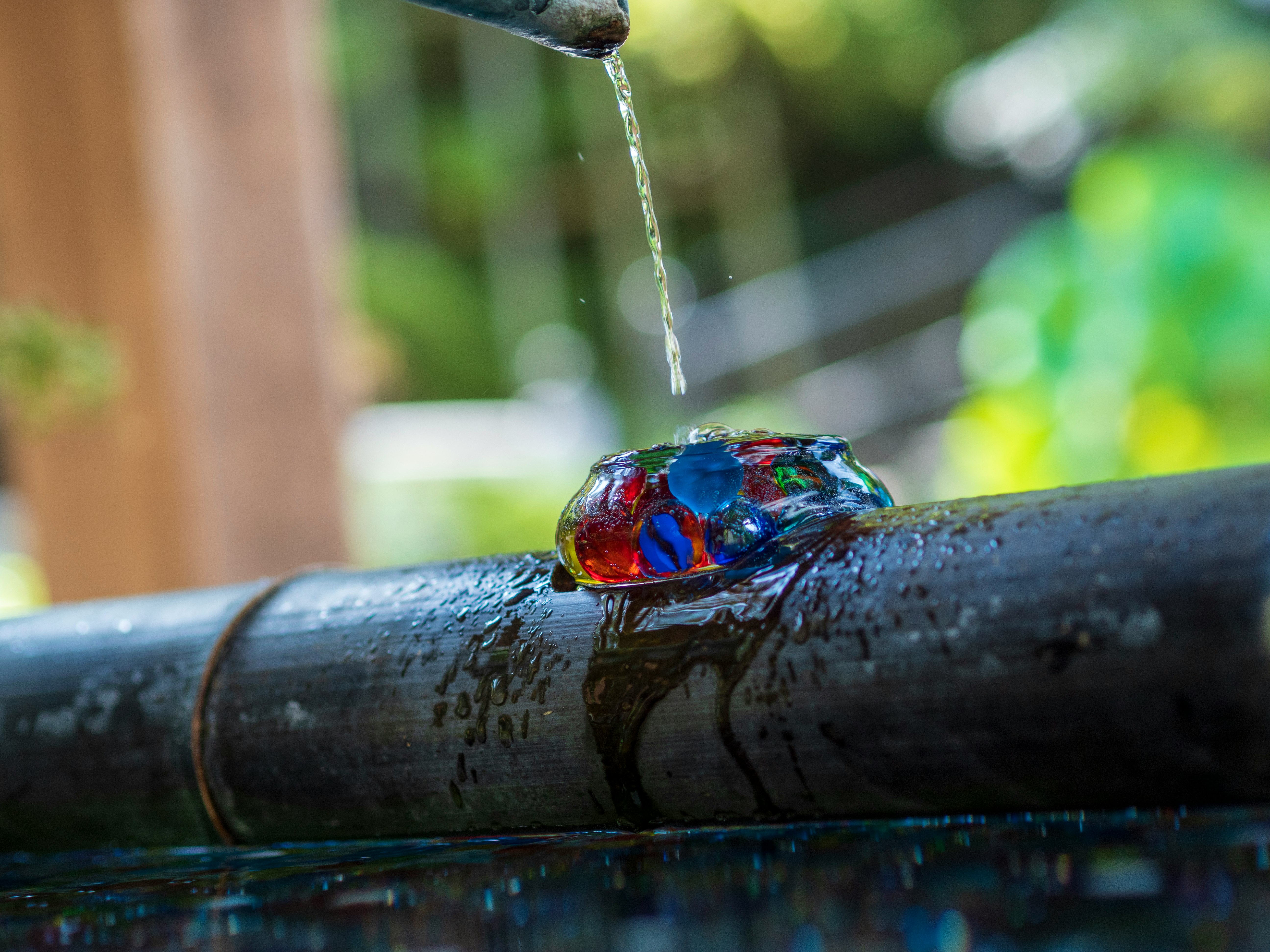 A colorful gem-like stone with water dripping on it in a natural setting