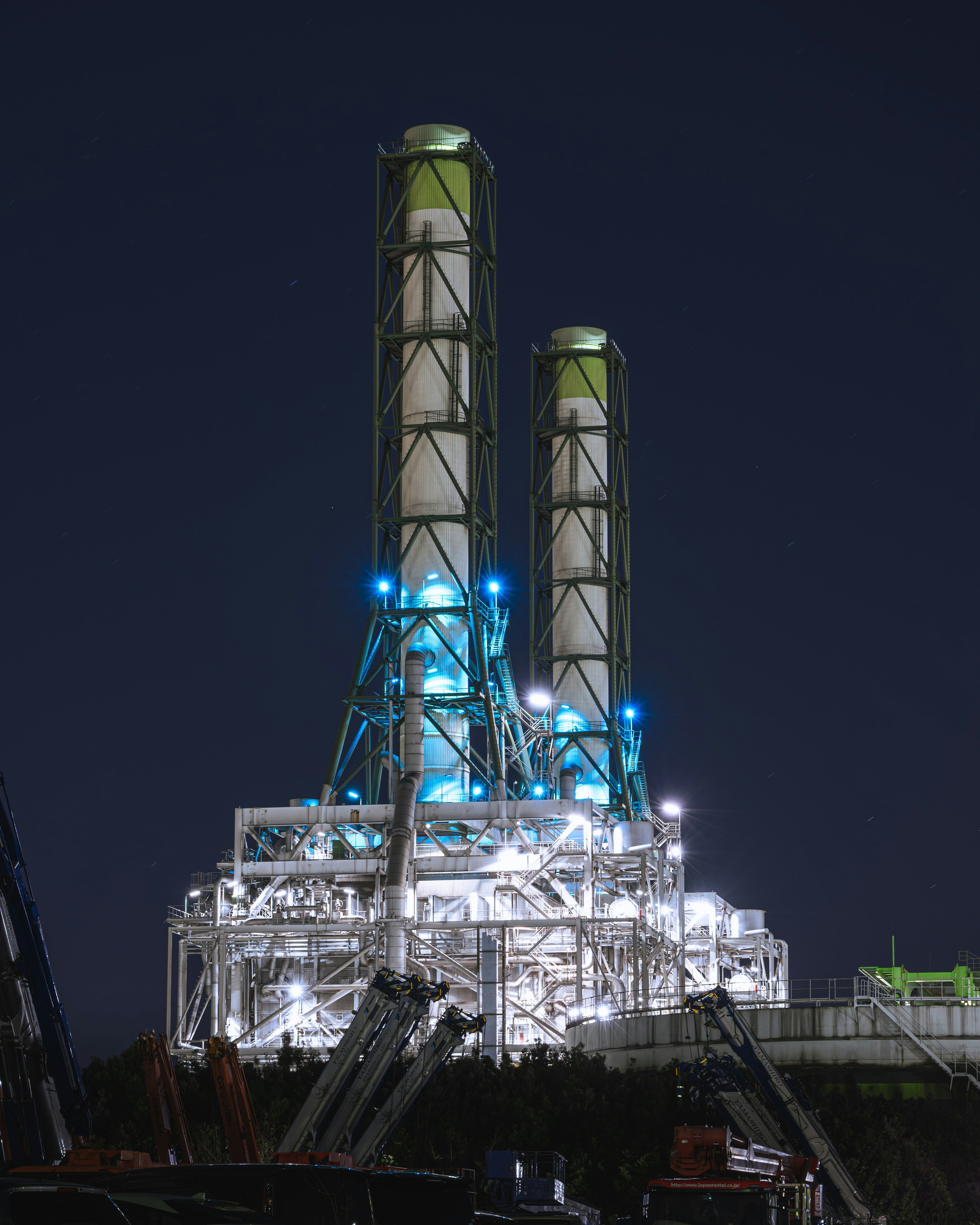 Night industrial plant with tall silos and piping