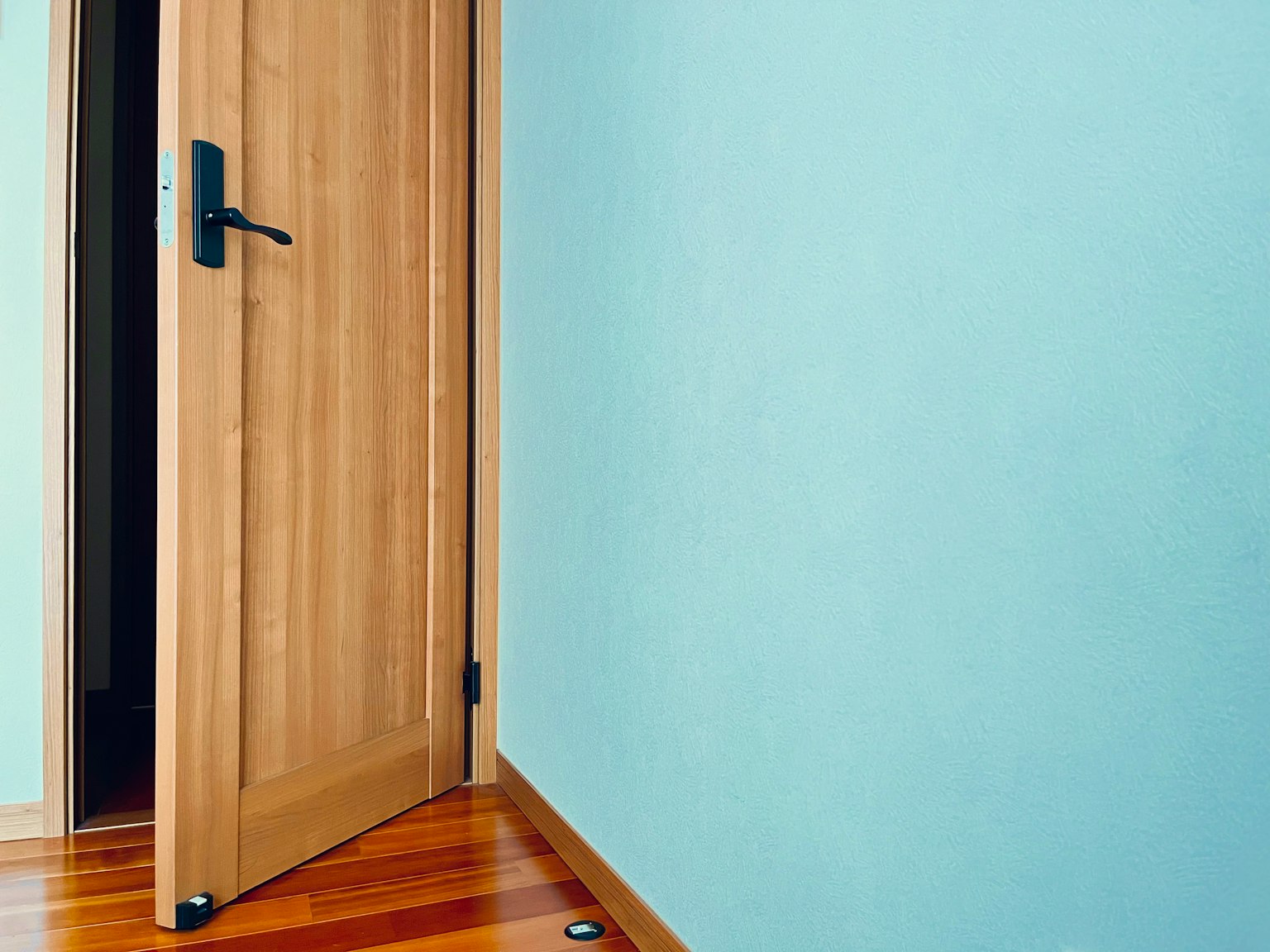 Una porta in legno leggermente aperta in una stanza con parete blu