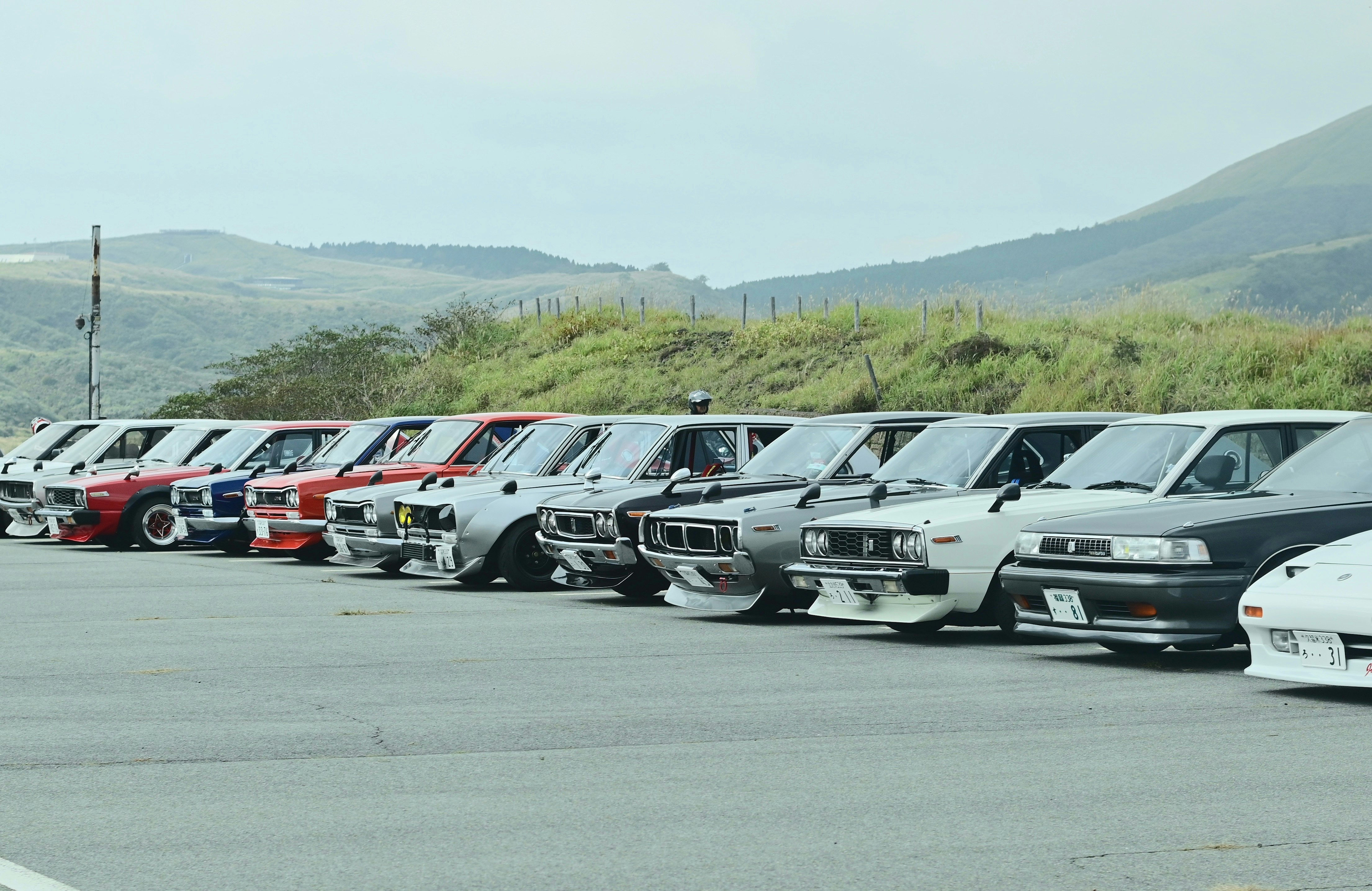 山の麓に並ぶクラシックカーの駐車列