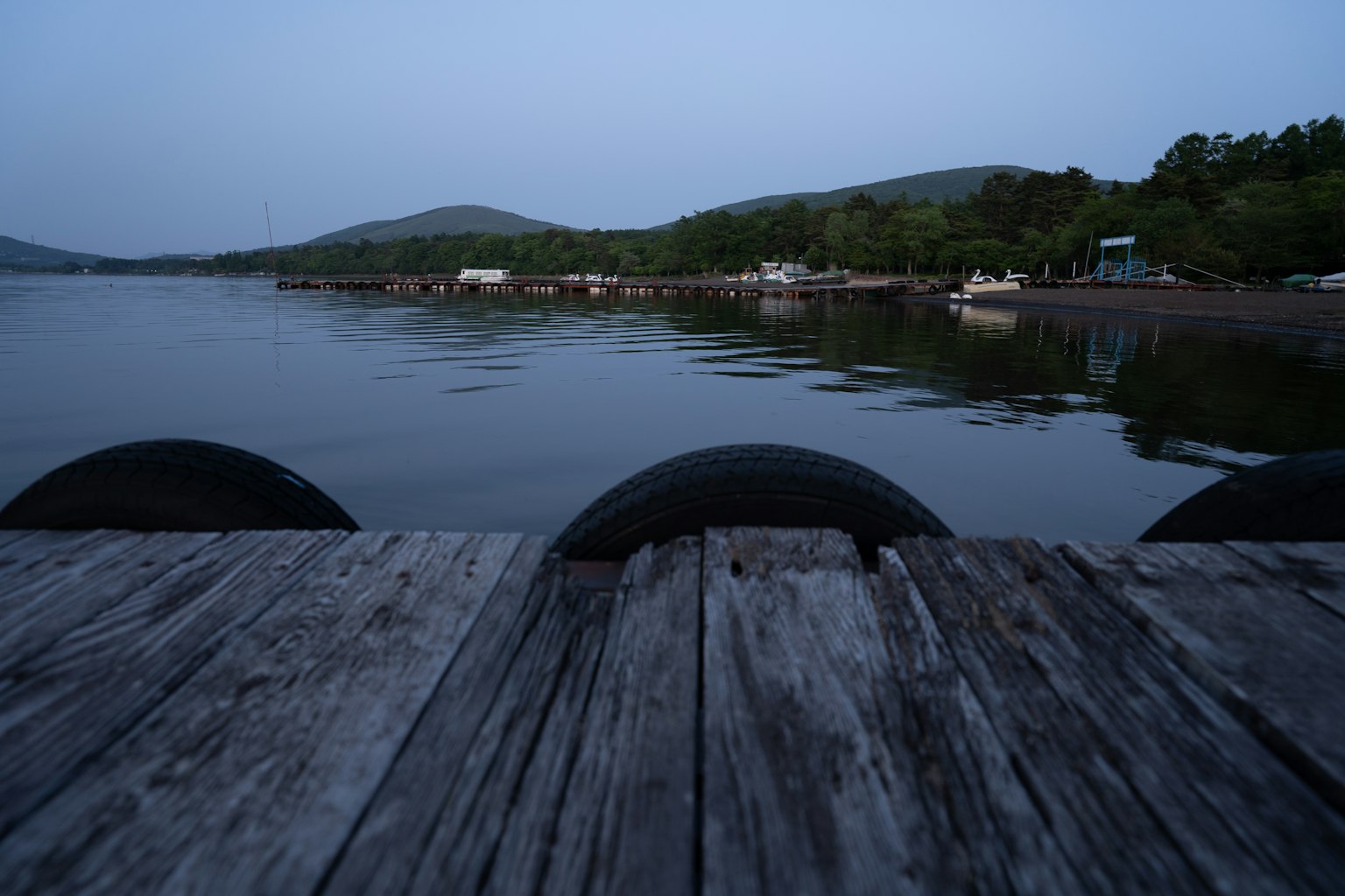Vista tranquila del lago con un muelle de madera cielo azul de la tarde reflejado en el agua