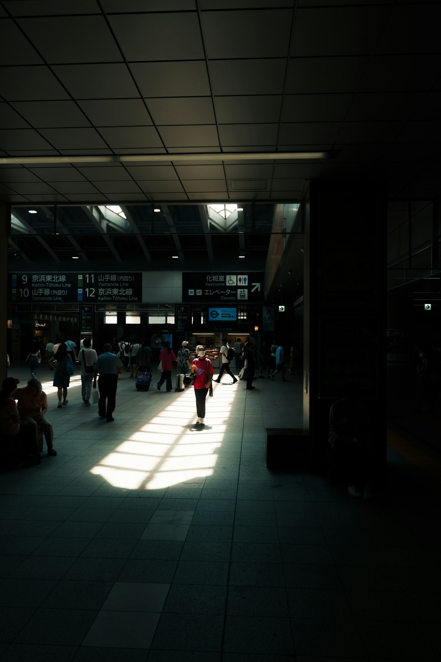 Interior brillante de una estación con personas y un rayo de luz en el suelo
