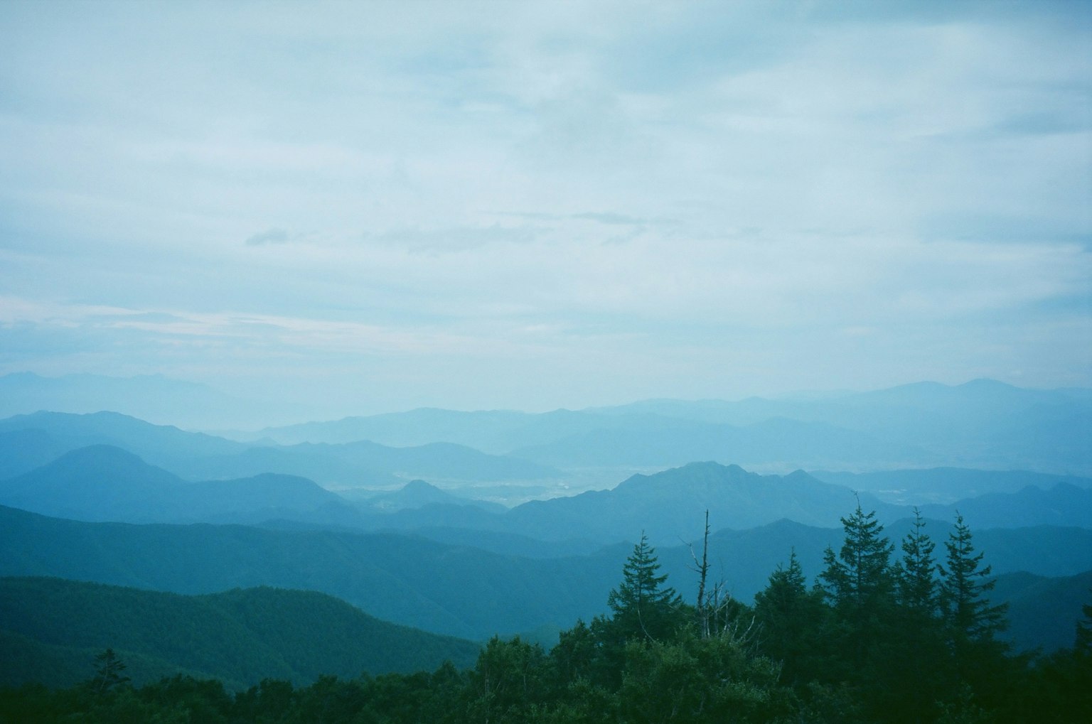 雾蒙蒙的风景与蓝色山脉和多云的天空