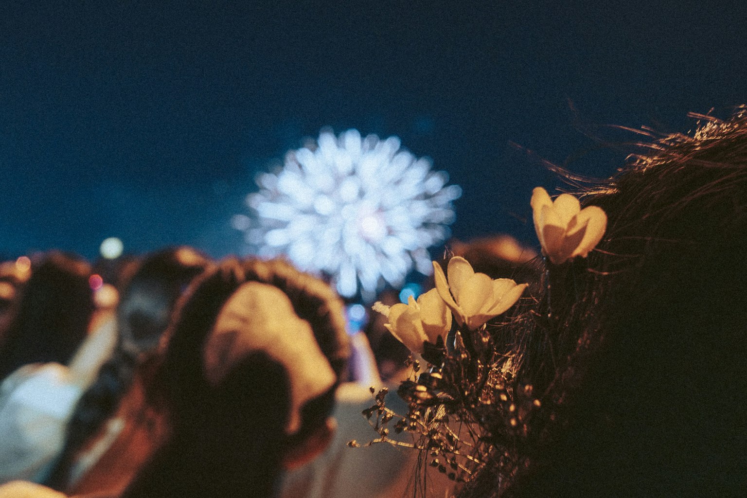 Folla che guarda i fuochi d'artificio nel cielo notturno con decorazioni floreali