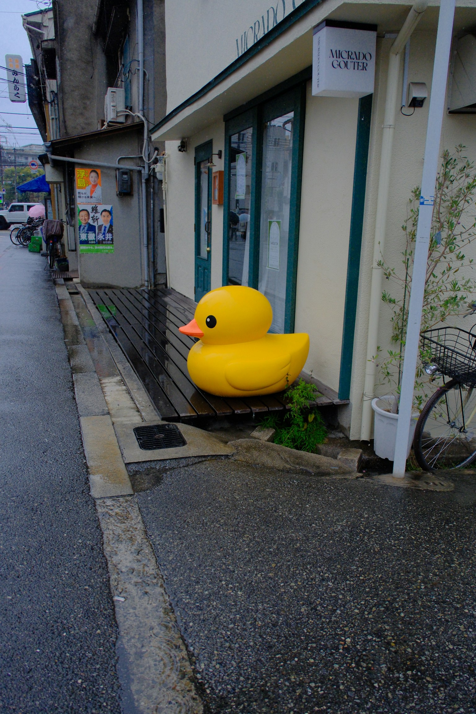 黄色いアヒルのオブジェが店舗の前に置かれている街の風景