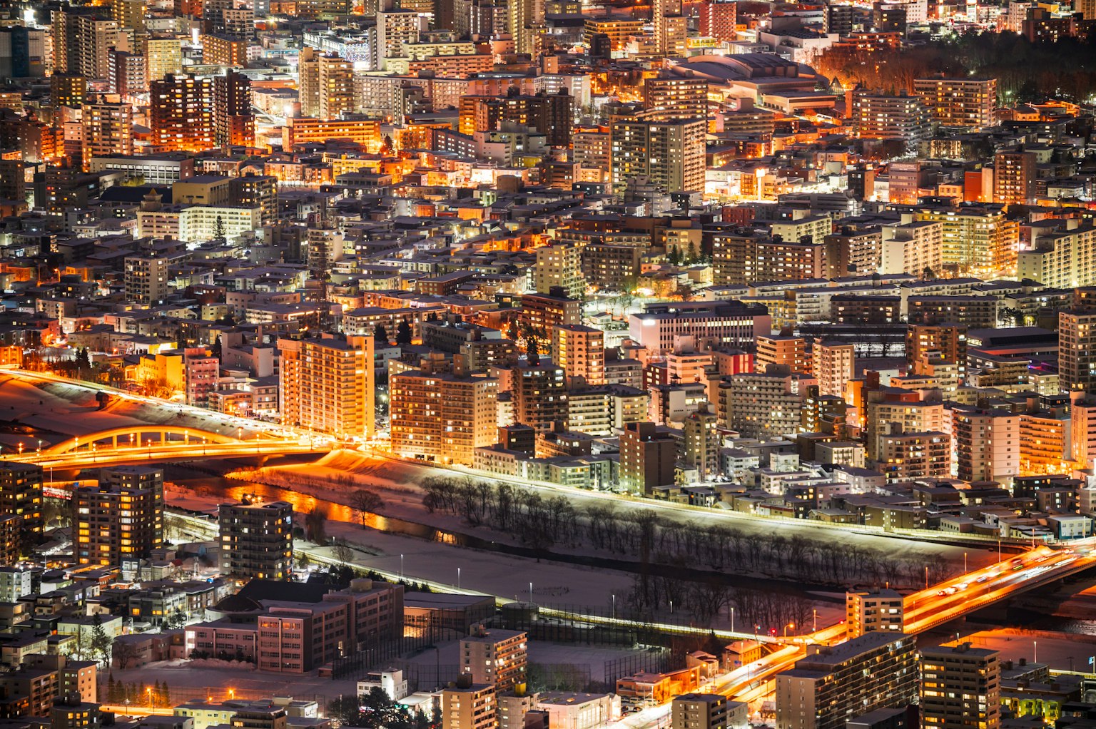 夜間城市的鳥瞰圖，燈光閃爍的建築和河上的橋