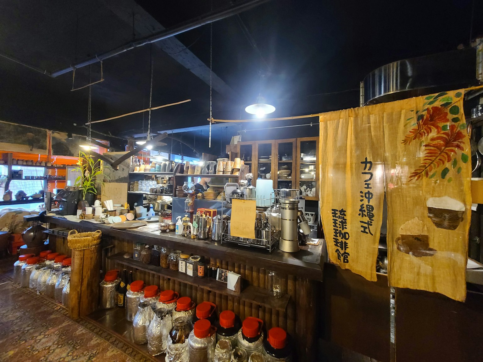 Interior de un izakaya con mostrador de madera y estanterías llenas de tarros noren tradicional colgando