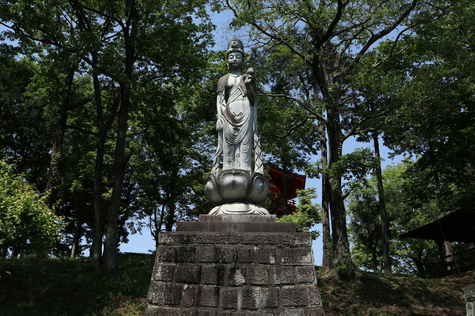 A statue of a Buddhist figure surrounded by green trees