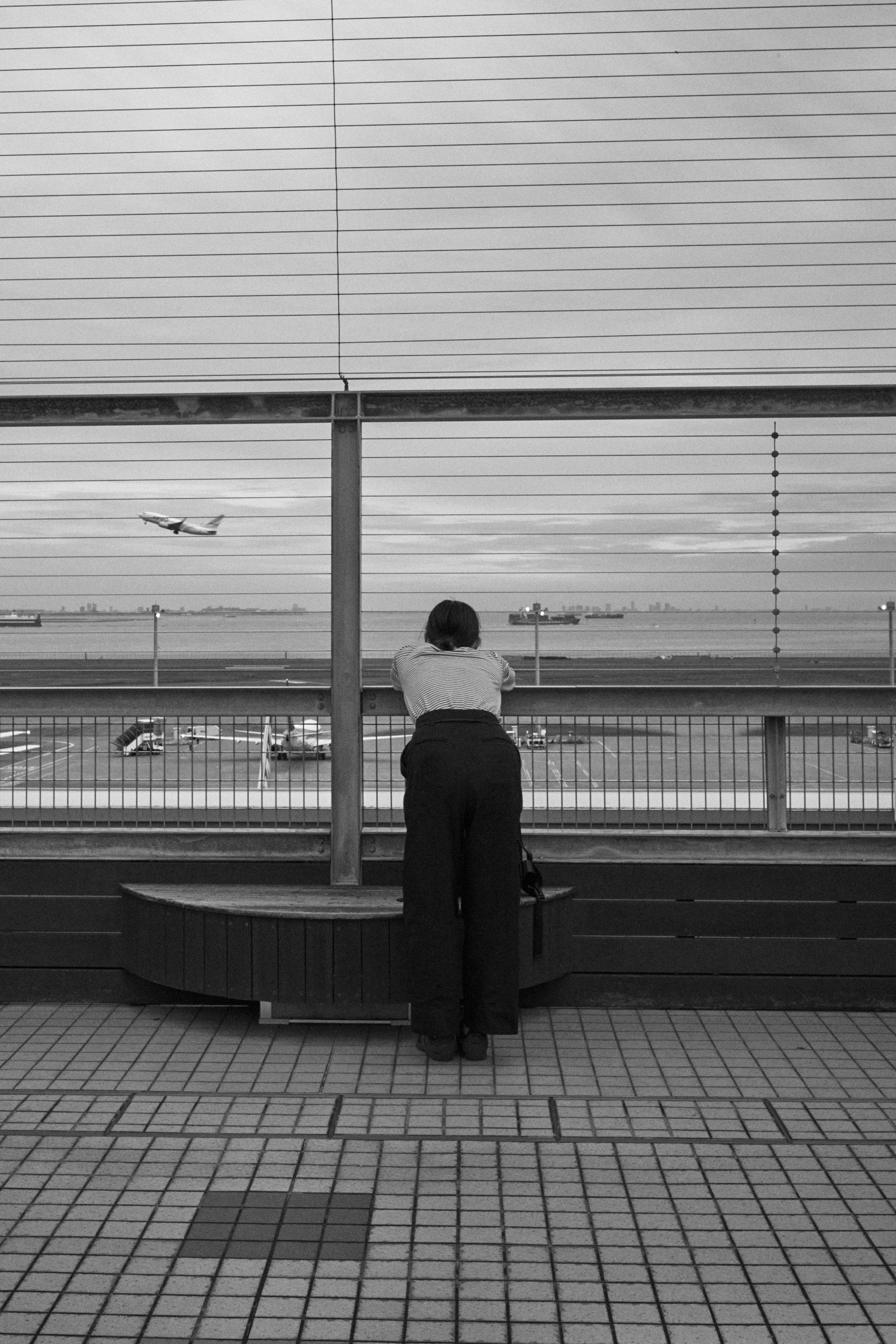 Une femme regardant par une fenêtre dans une scène en noir et blanc