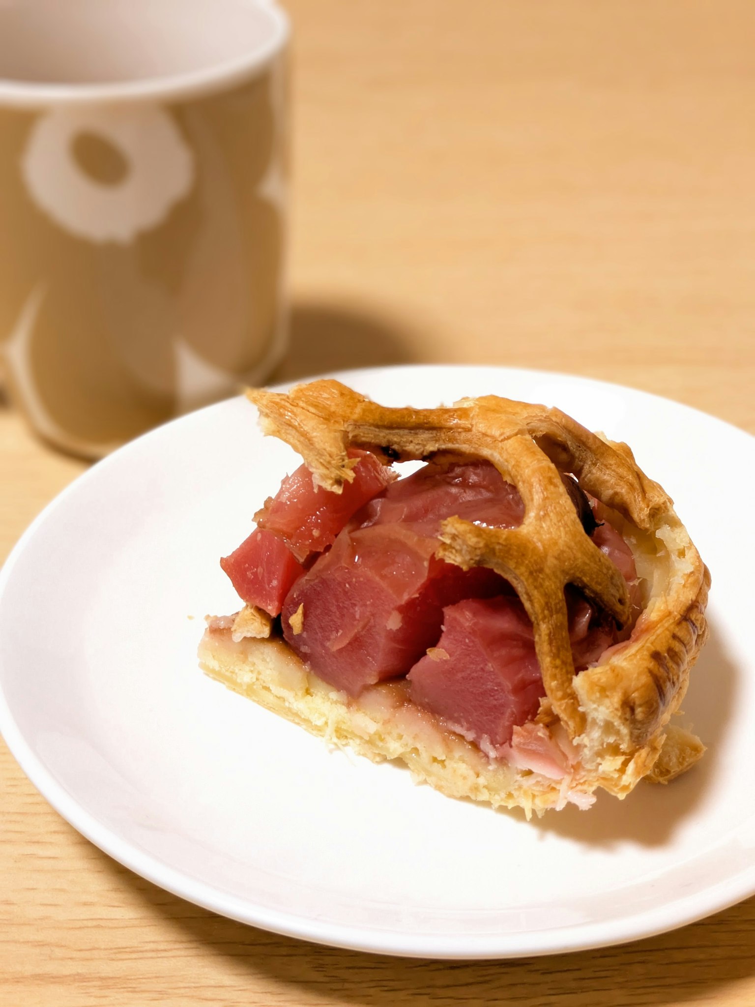 Una rebanada de pastel en un plato con una taza de café al fondo