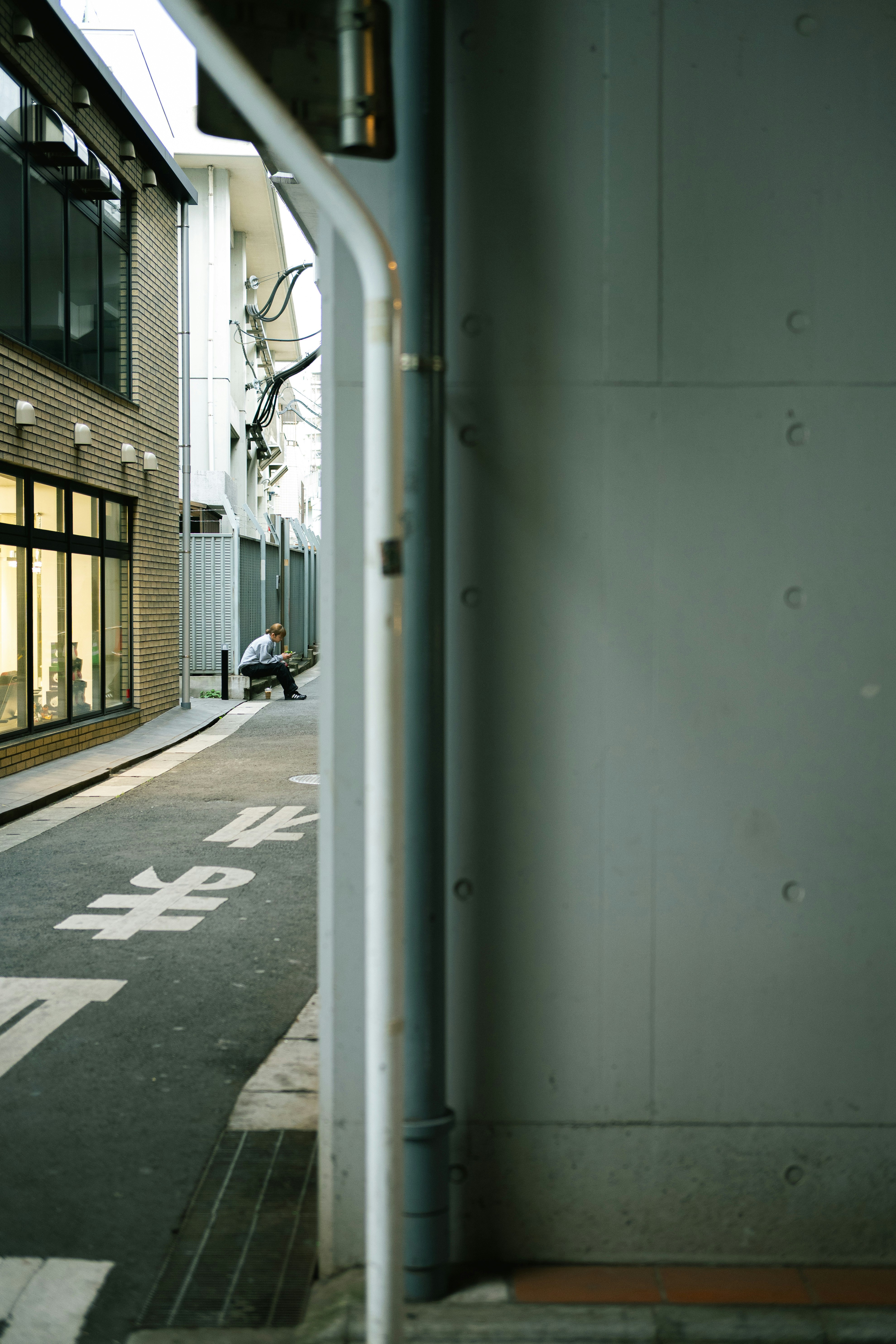 A street view showing a narrow corner with a wall and buildings