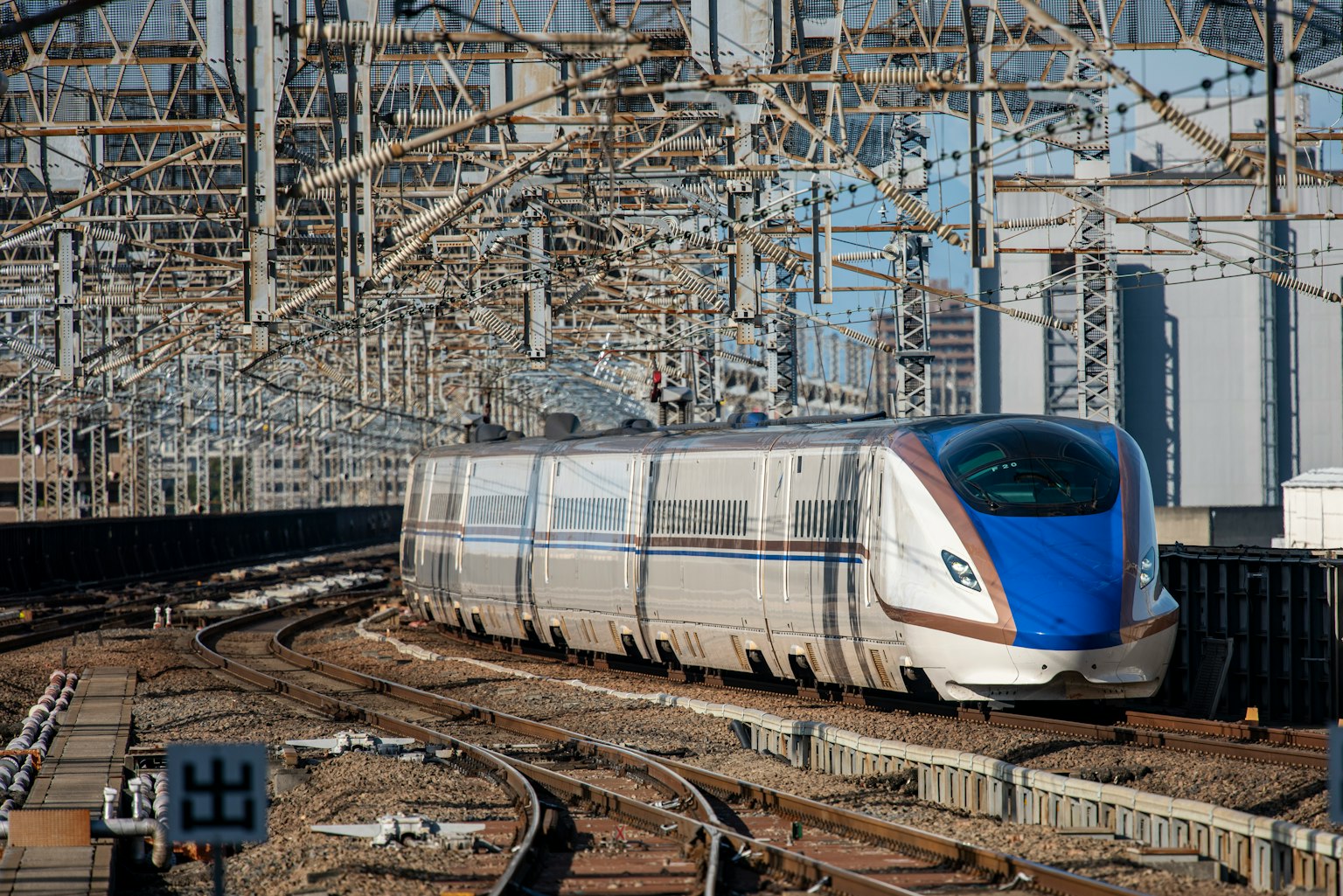 รถไฟชินคันเซนที่มีส่วนหน้าสีน้ำเงินวิ่งอยู่บนราง