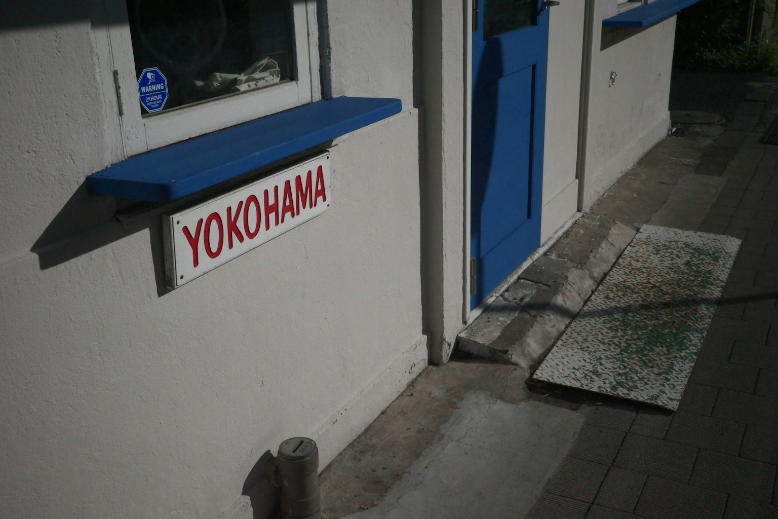 Esterno di un edificio con pareti bianche e telai delle finestre blu con un'insegna che dice YOKOHAMA
