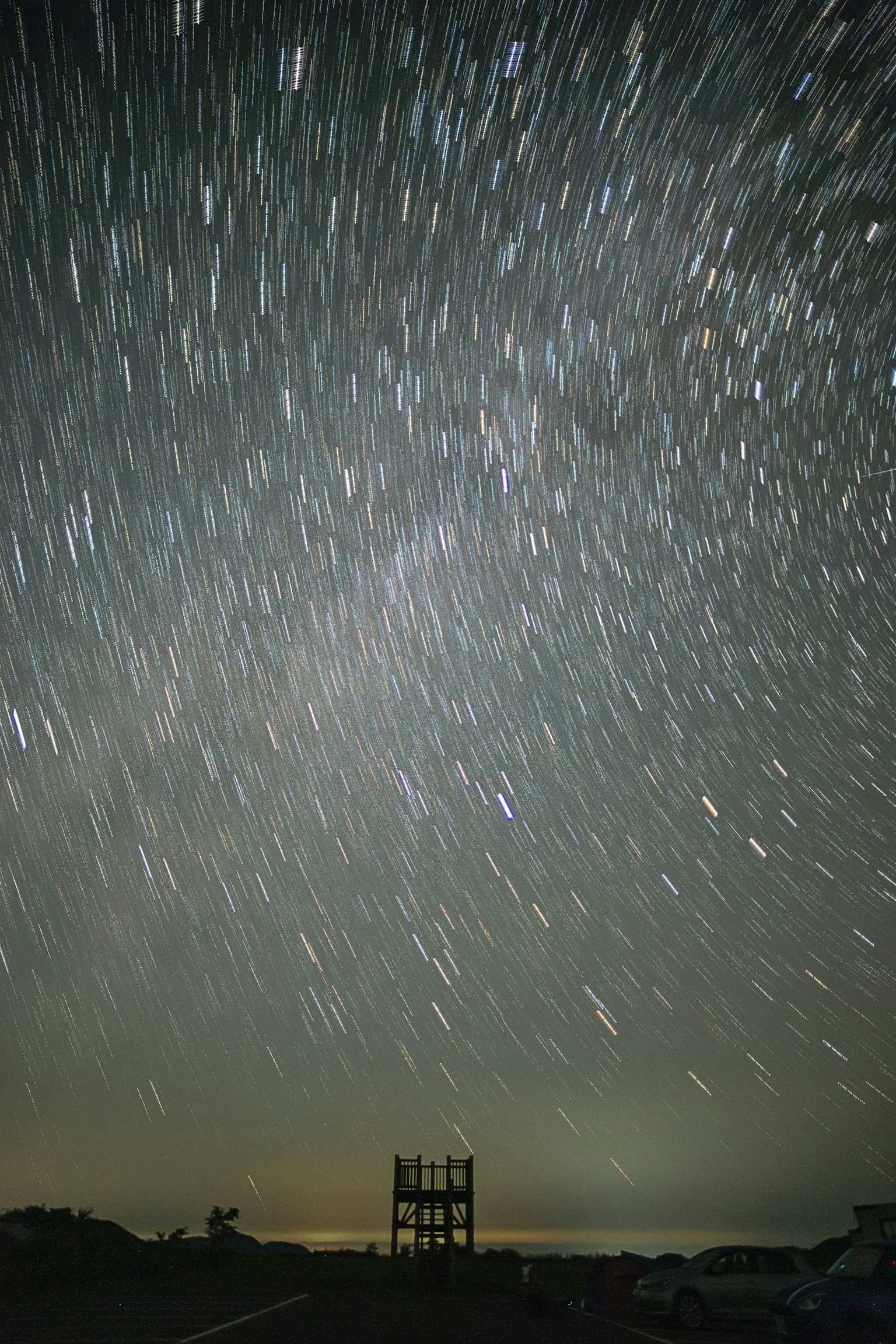 Tracce di stelle visibili in un cielo notturno con una struttura in silhouette