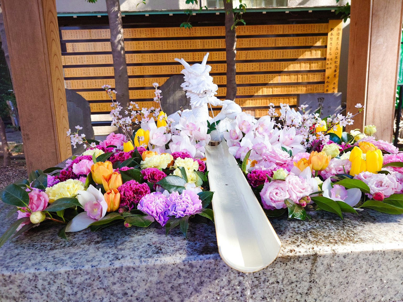 Una scultura di drago bianco circondata da fiori colorati