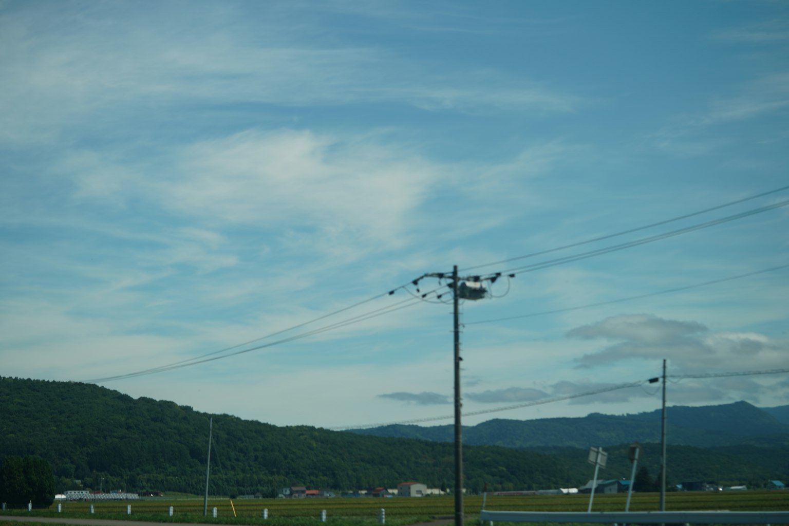 Landschaft mit blauem Himmel Wolken Bergen und einem Strommast