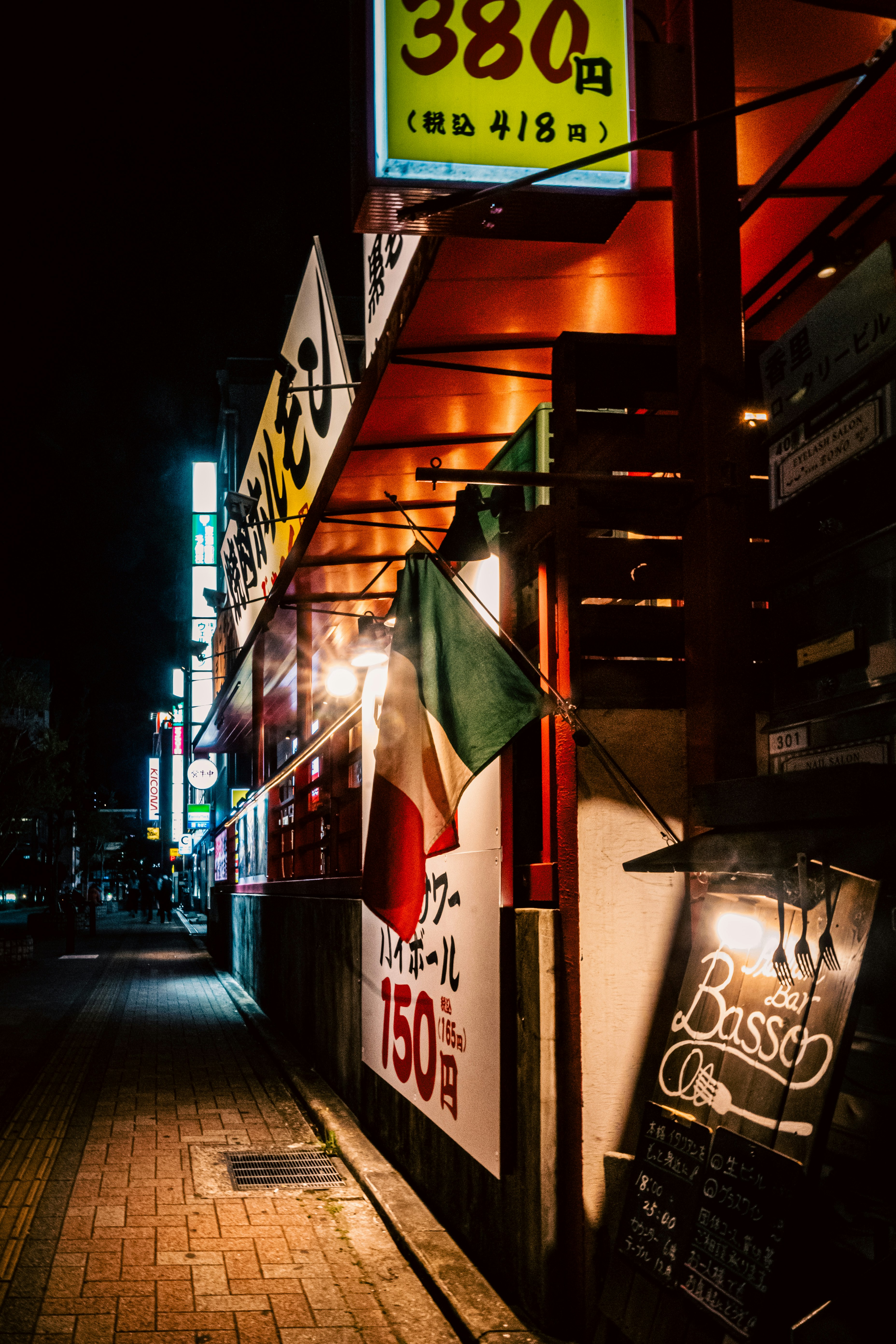夜の路地に並ぶ看板と提灯のある飲食店の軒先
