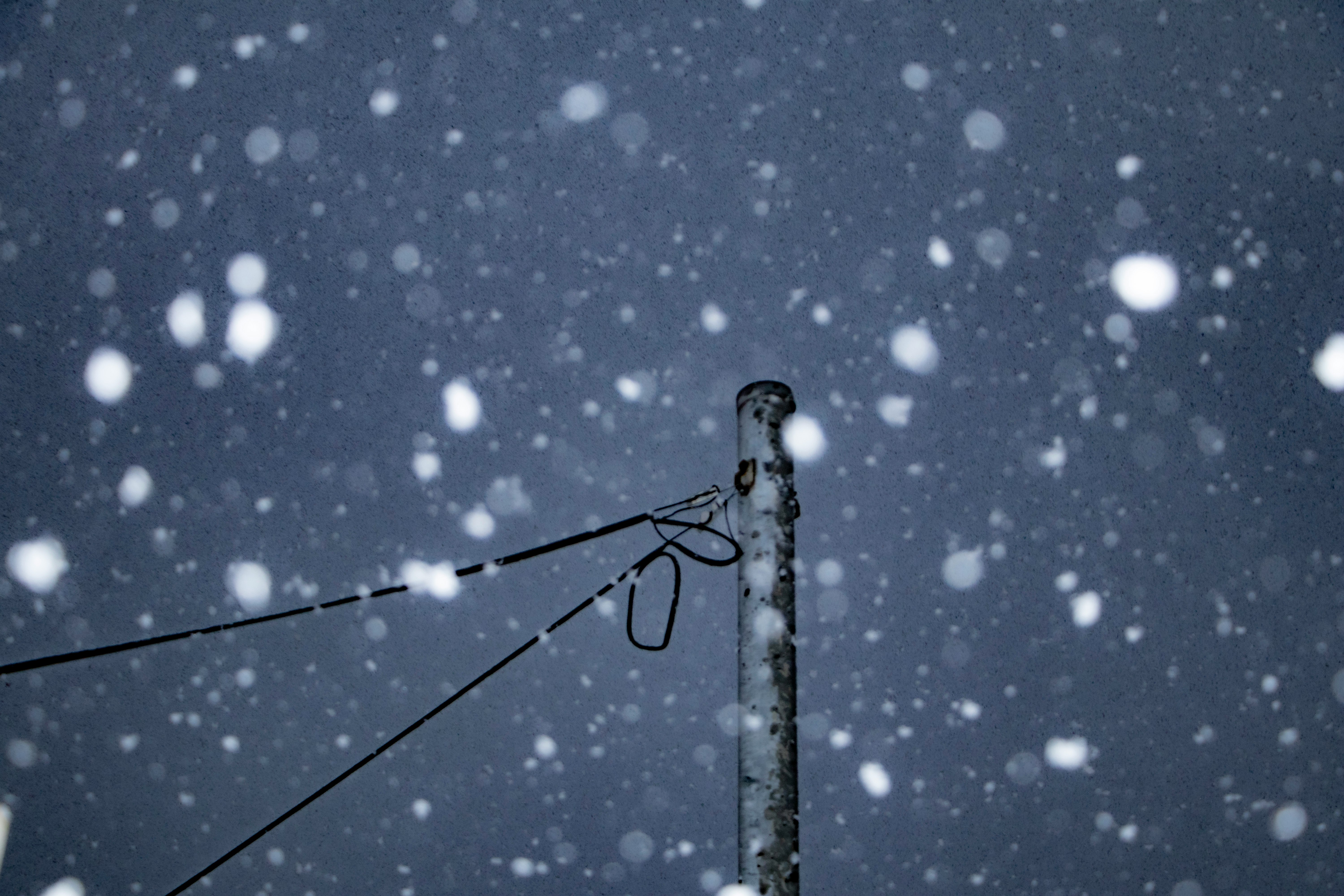 降りしきる雪の中の細い電線と支柱