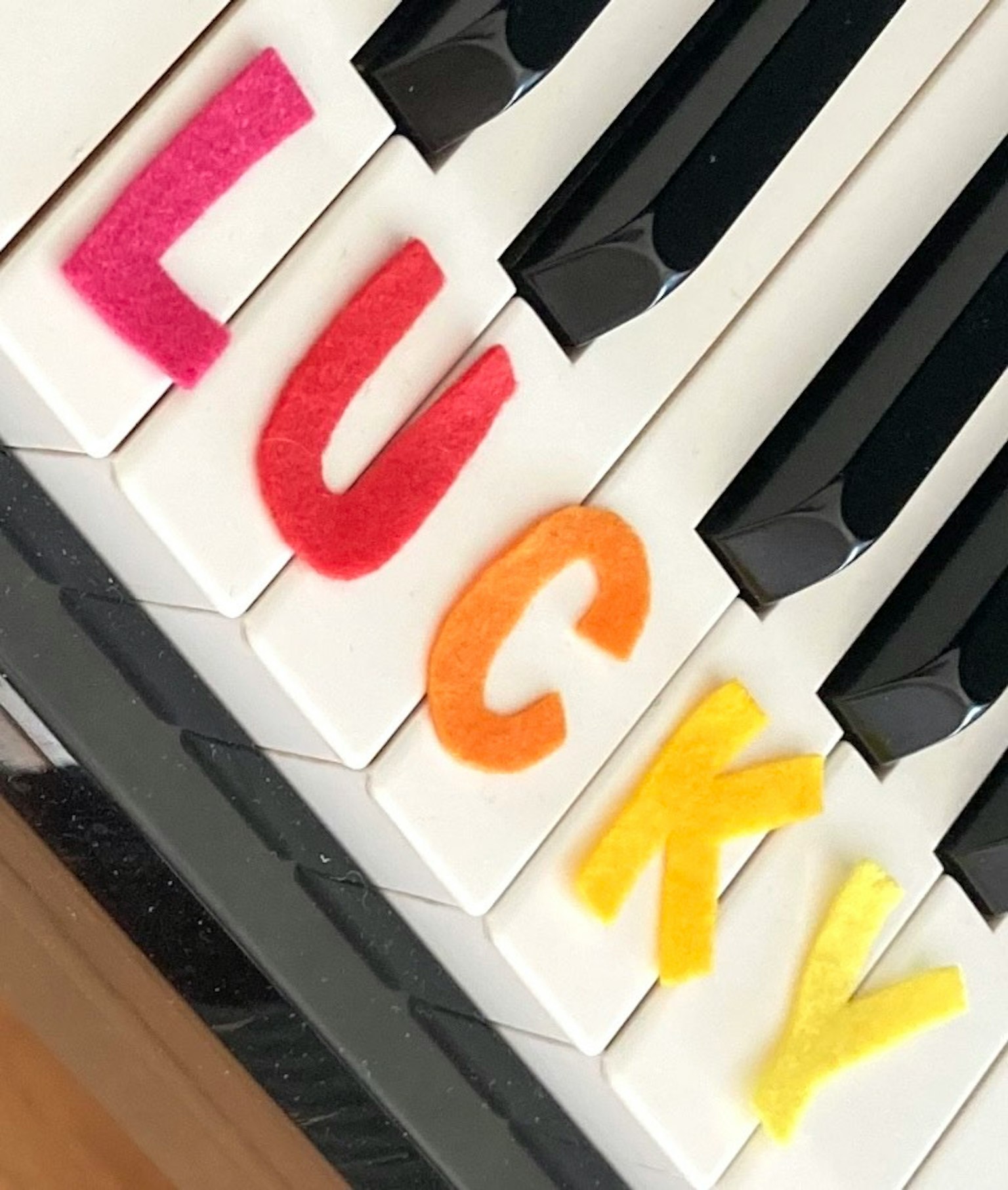 在钢琴键上拼写'LUCKY'的彩色字母
