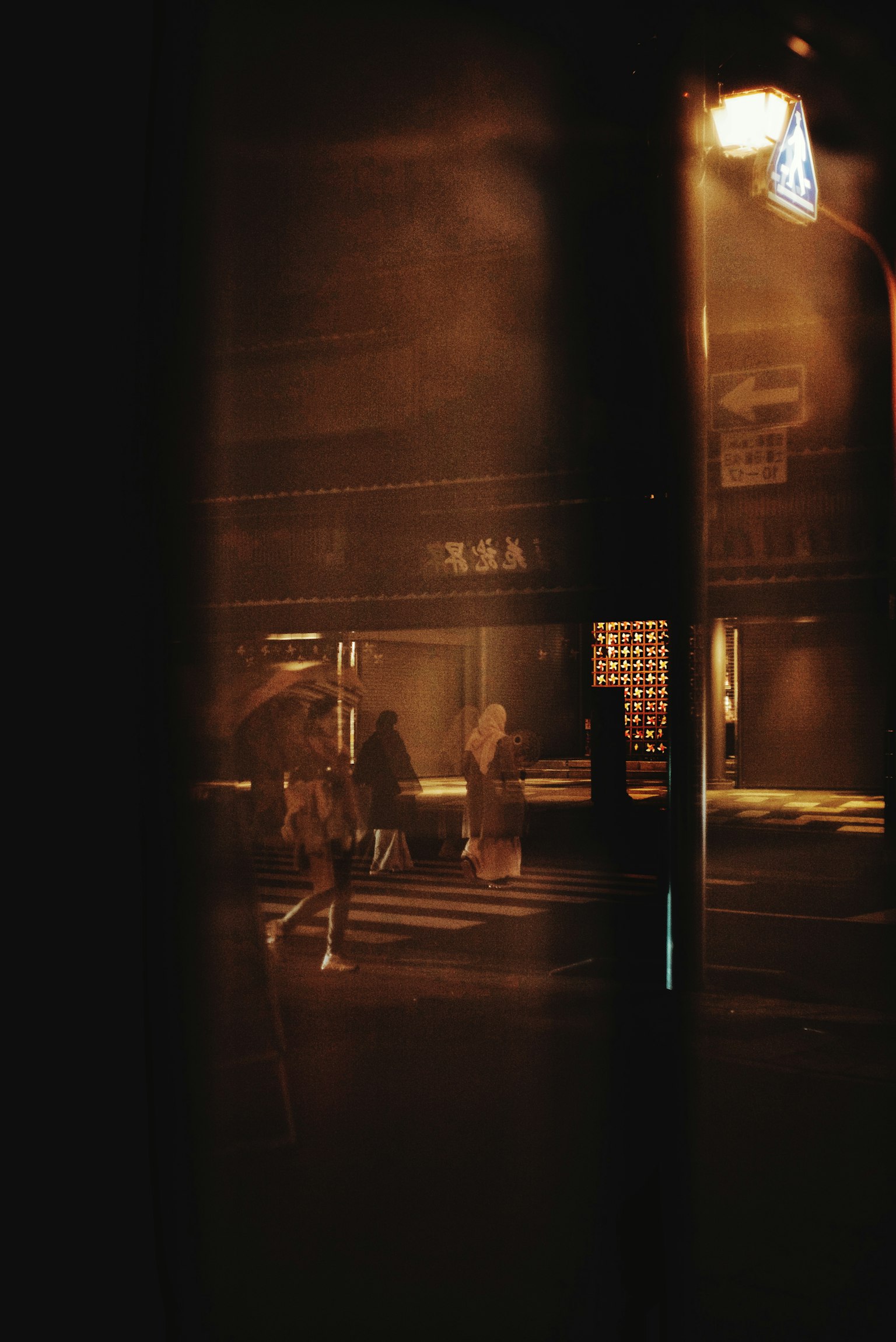 Silhouettes of people walking in the night city with streetlight glow