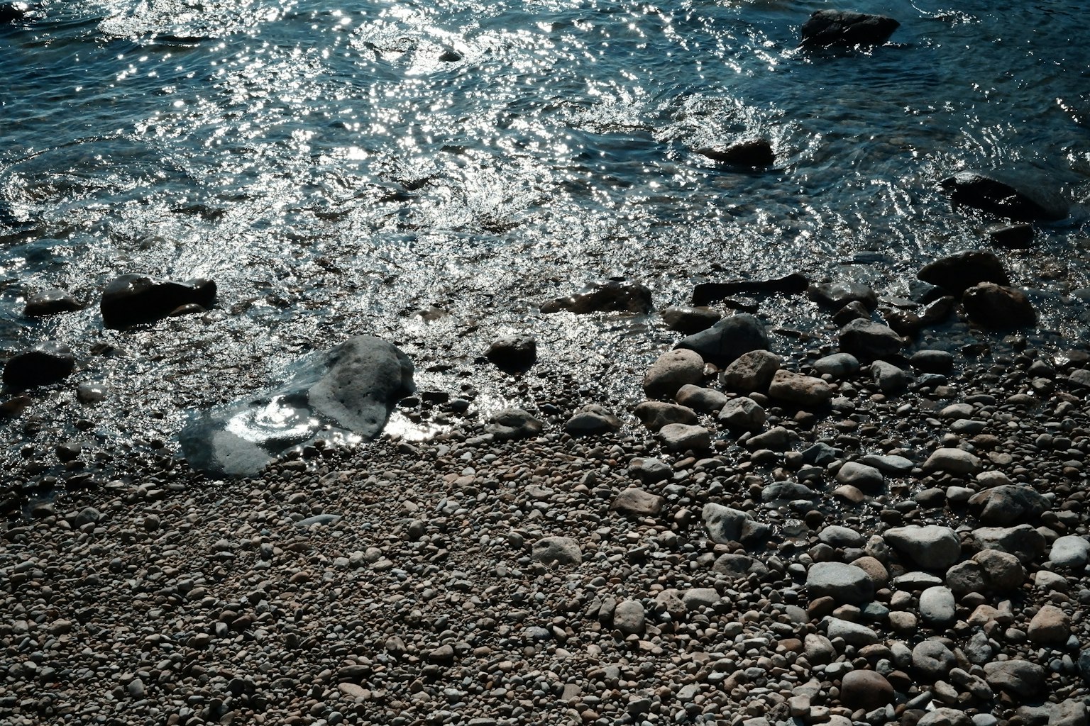 Una riva con pietre sparse e superficie d'acqua scintillante