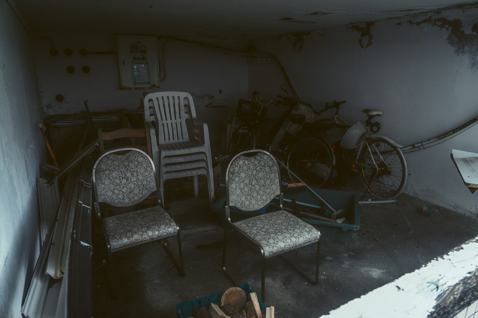 Una stanza poco illuminata con due sedie e una bicicletta sullo sfondo