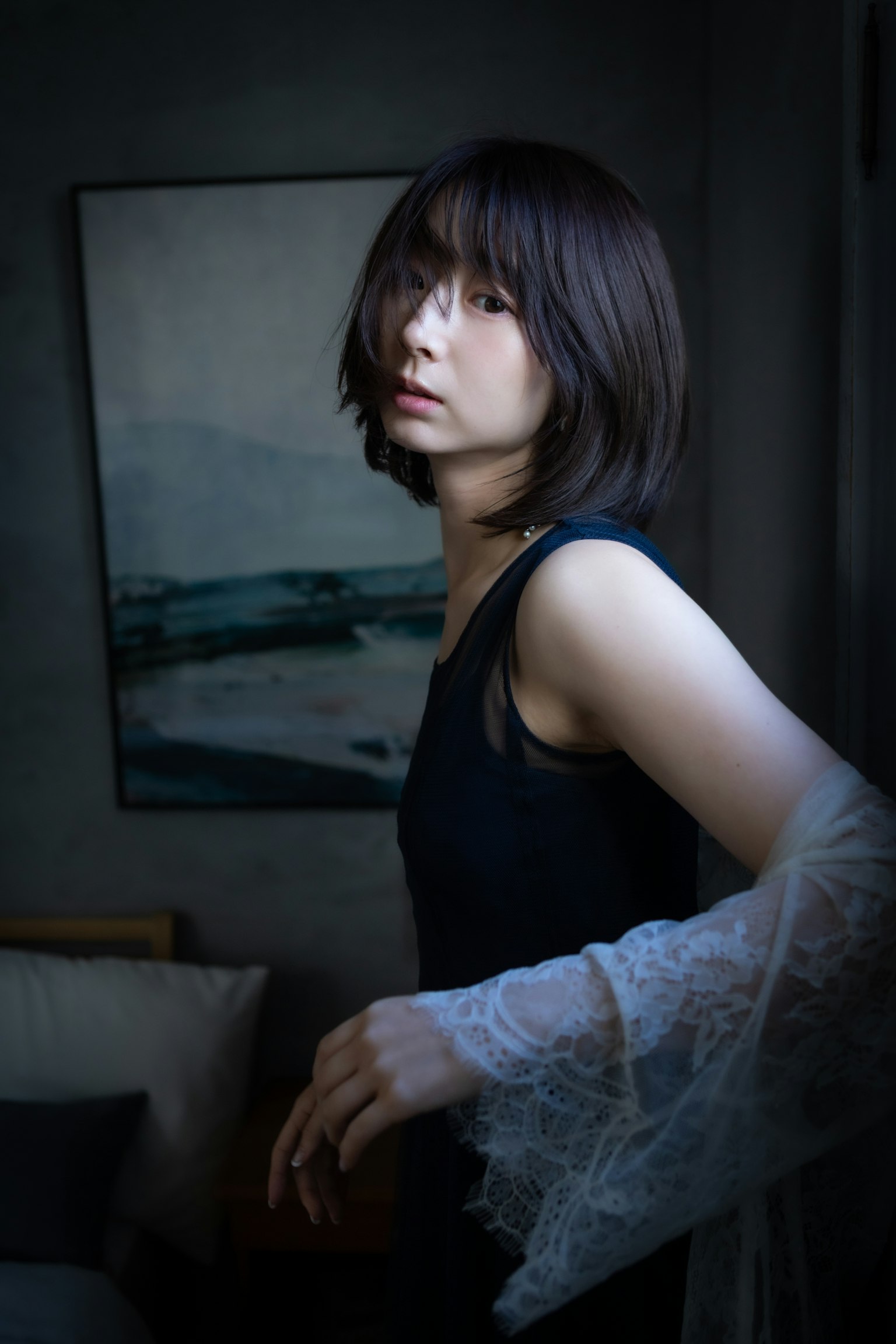 在黑暗背景前摆姿势的女性肖像 穿着黑色连衣裙和蕾丝袖子 头发及肩自然垂落