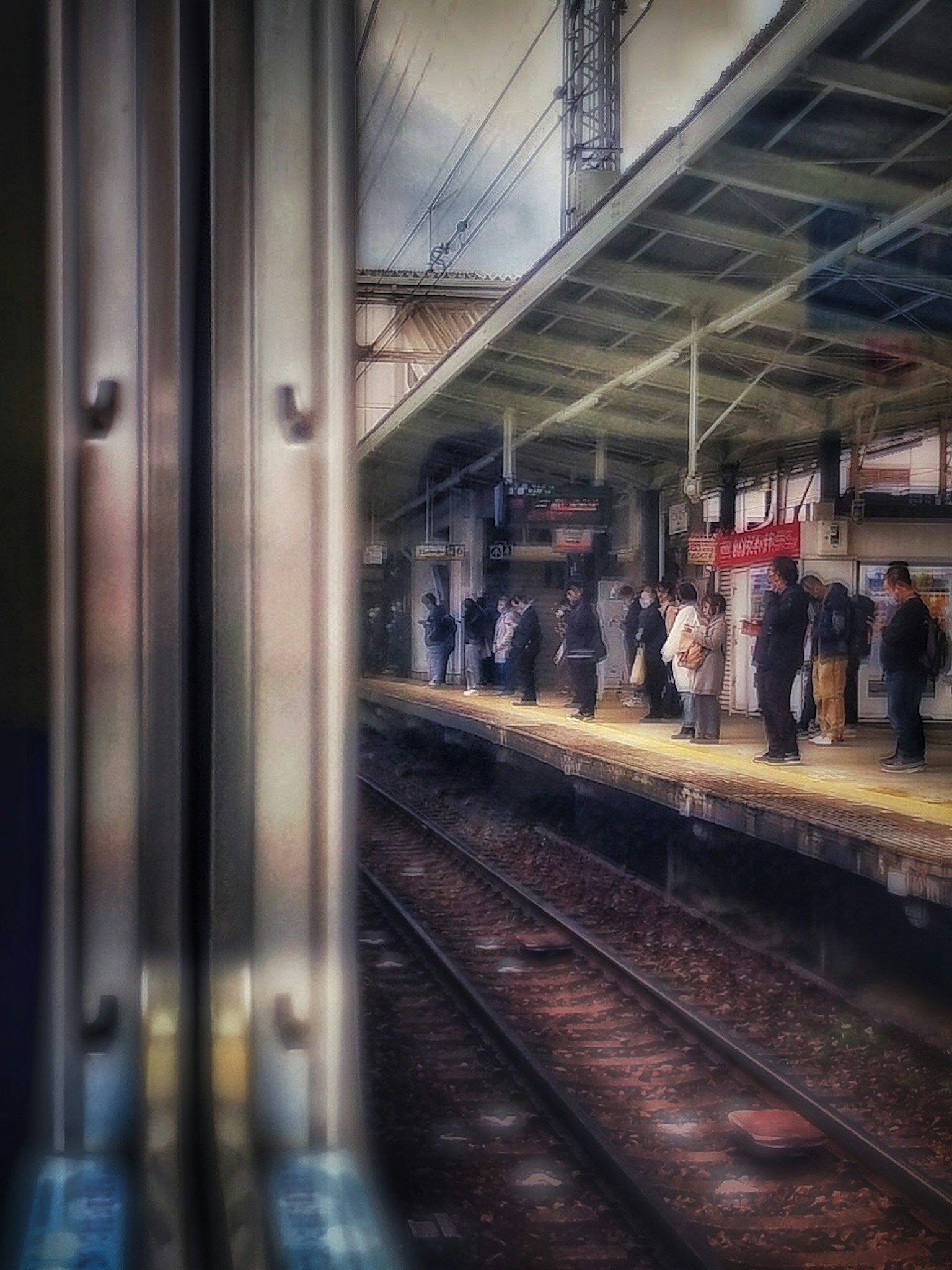 電車の窓から見た駅のプラットフォームに立つ人々