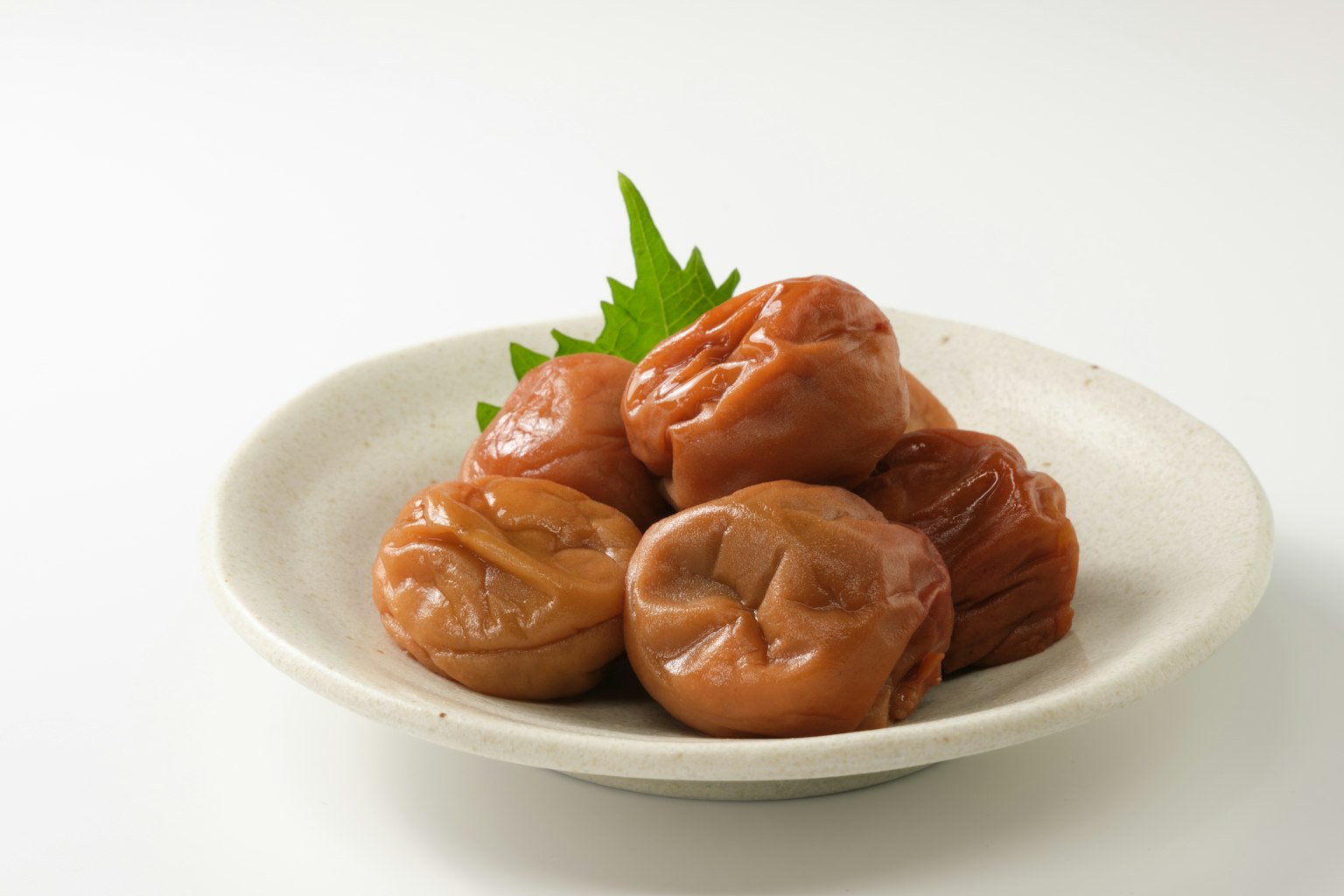 白色盘子上的腌梅和紫苏叶