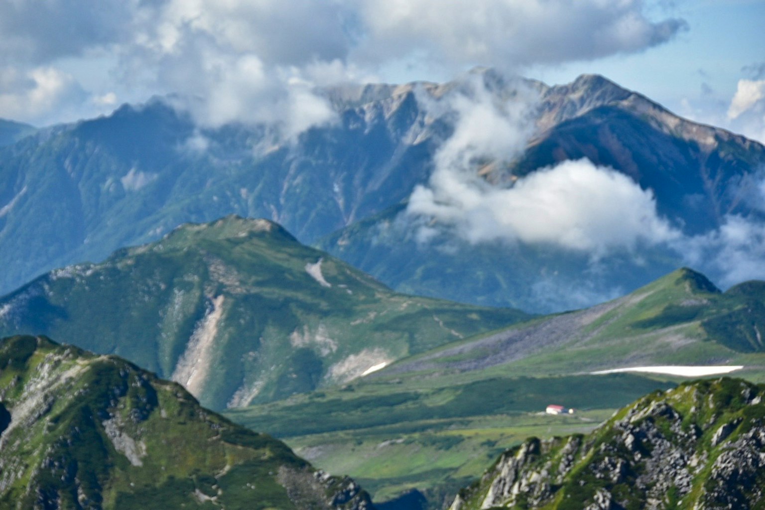 ทิวทัศน์ภูเขาที่สวยงามมีเมฆเนินเขาสีเขียวและหิมะ