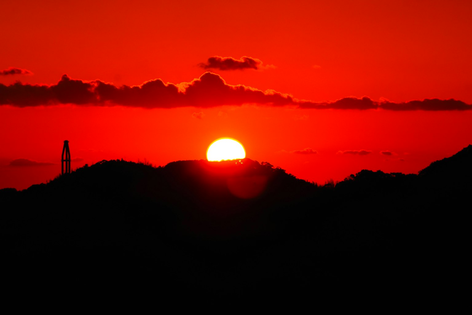 Beautiful sunset with a red sun setting behind the hills