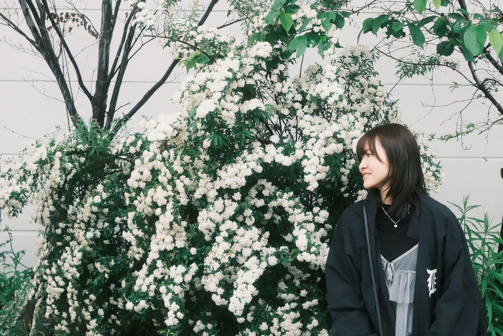 白い花の生け垣の前に立つ女性