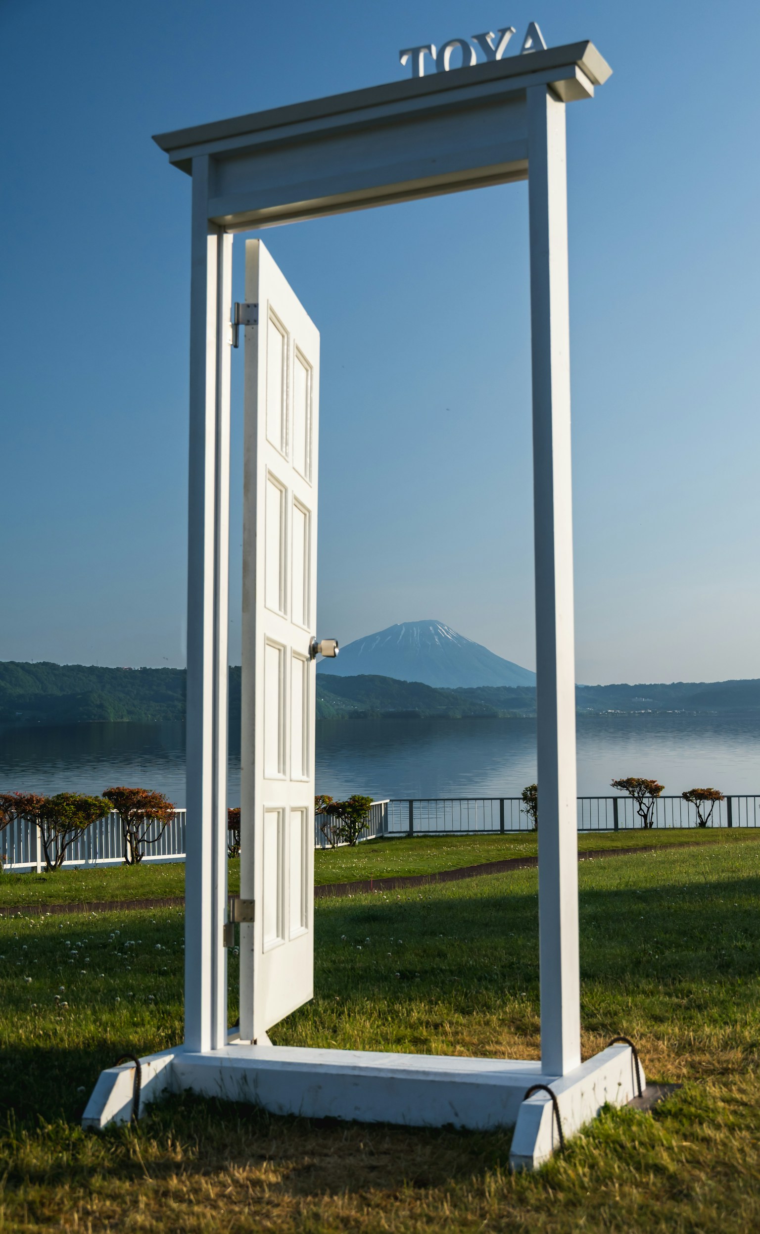 Sebuah pintu putih terbuka dengan pemandangan indah danau dan gunung di latar belakang