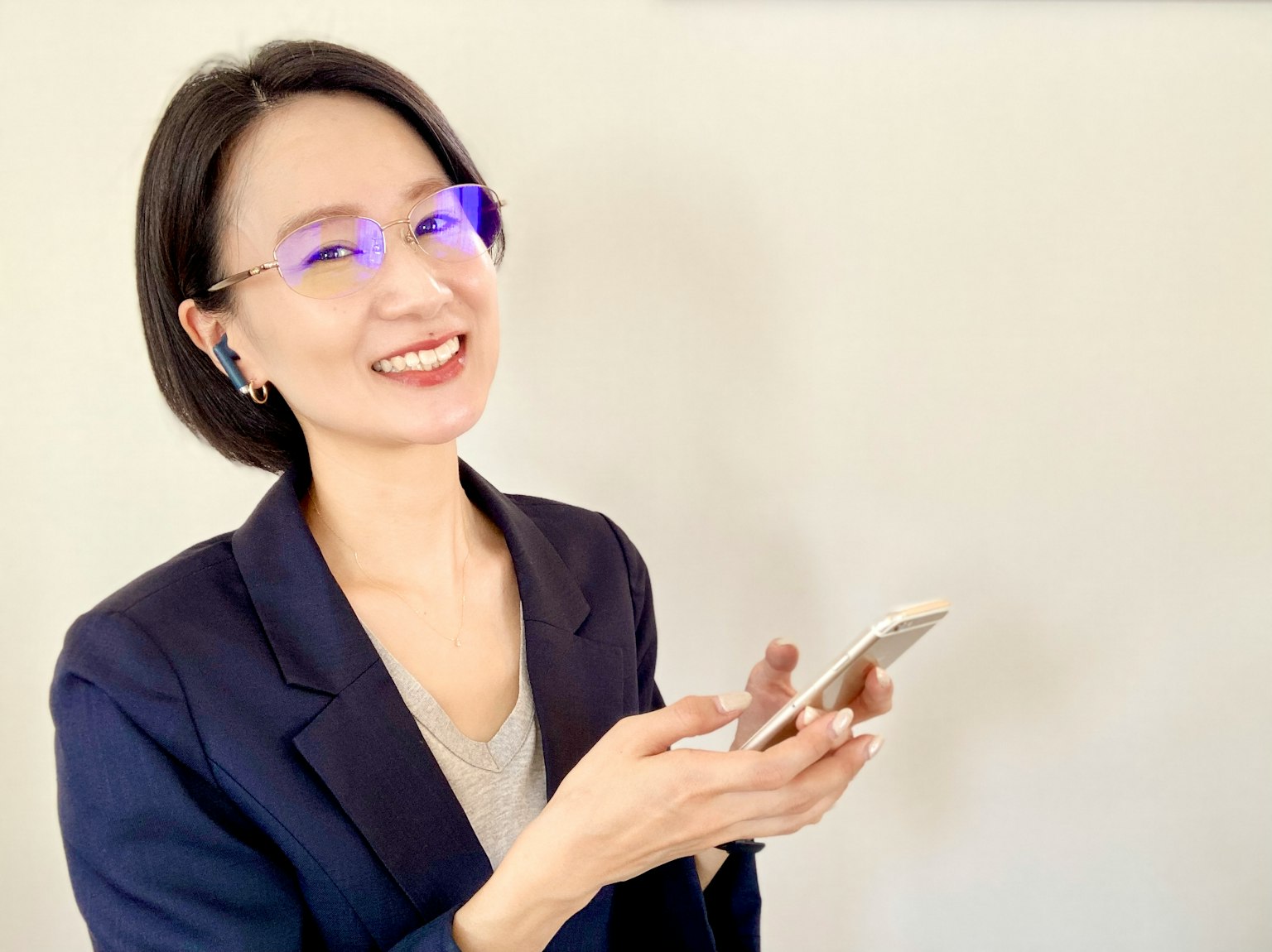 微笑的女性肖像手持智能手机佩戴蓝色眼镜商业风格